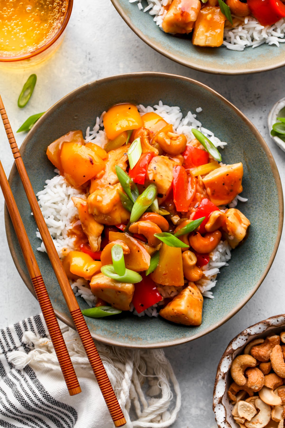 Two bowls of sweet and sour chicken styled on a gray surface.