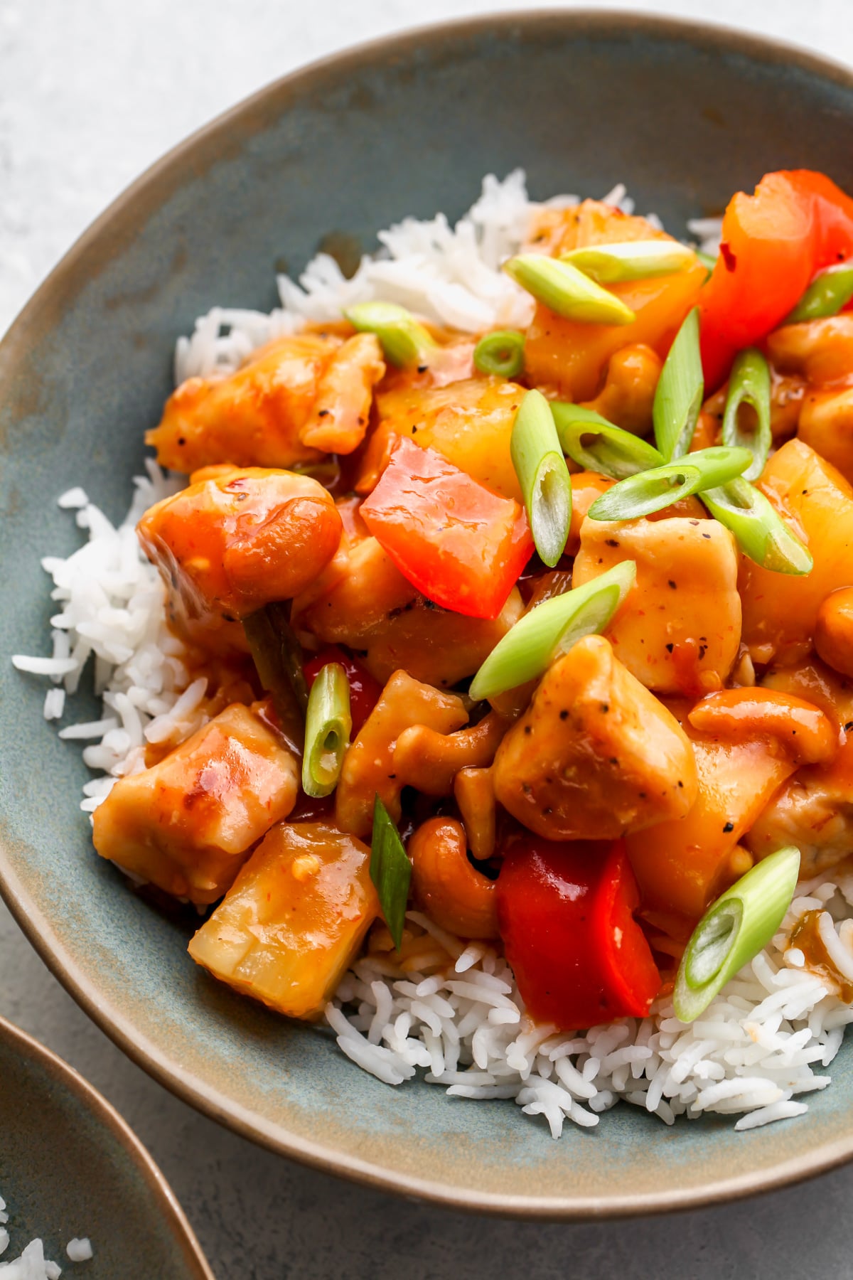 Sweet and sour chicken, peppers, and pineapple served over rice in a blue bowl.