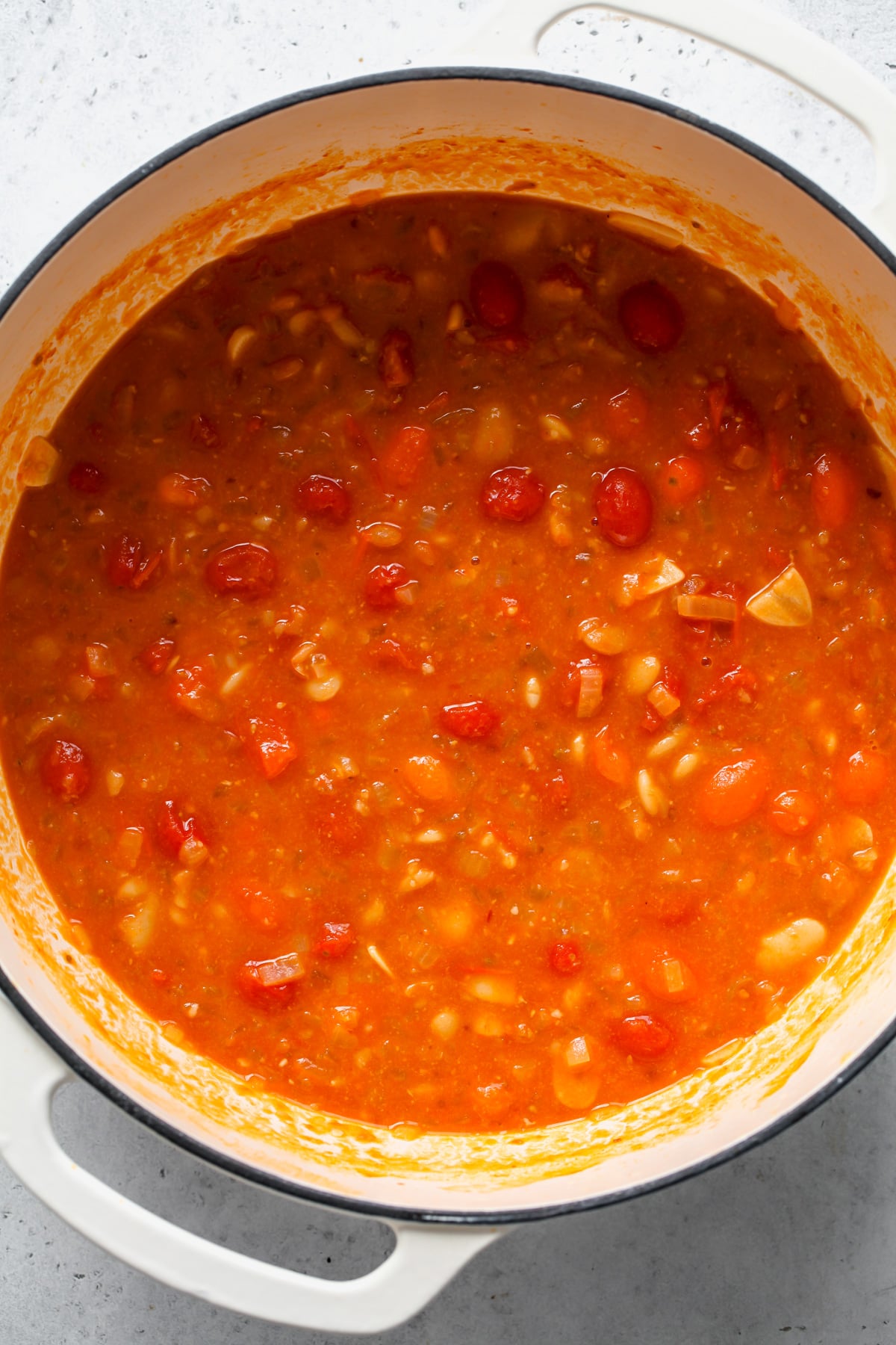 Tomato and butter bean stew after it finishes cooking in a white Dutch oven.