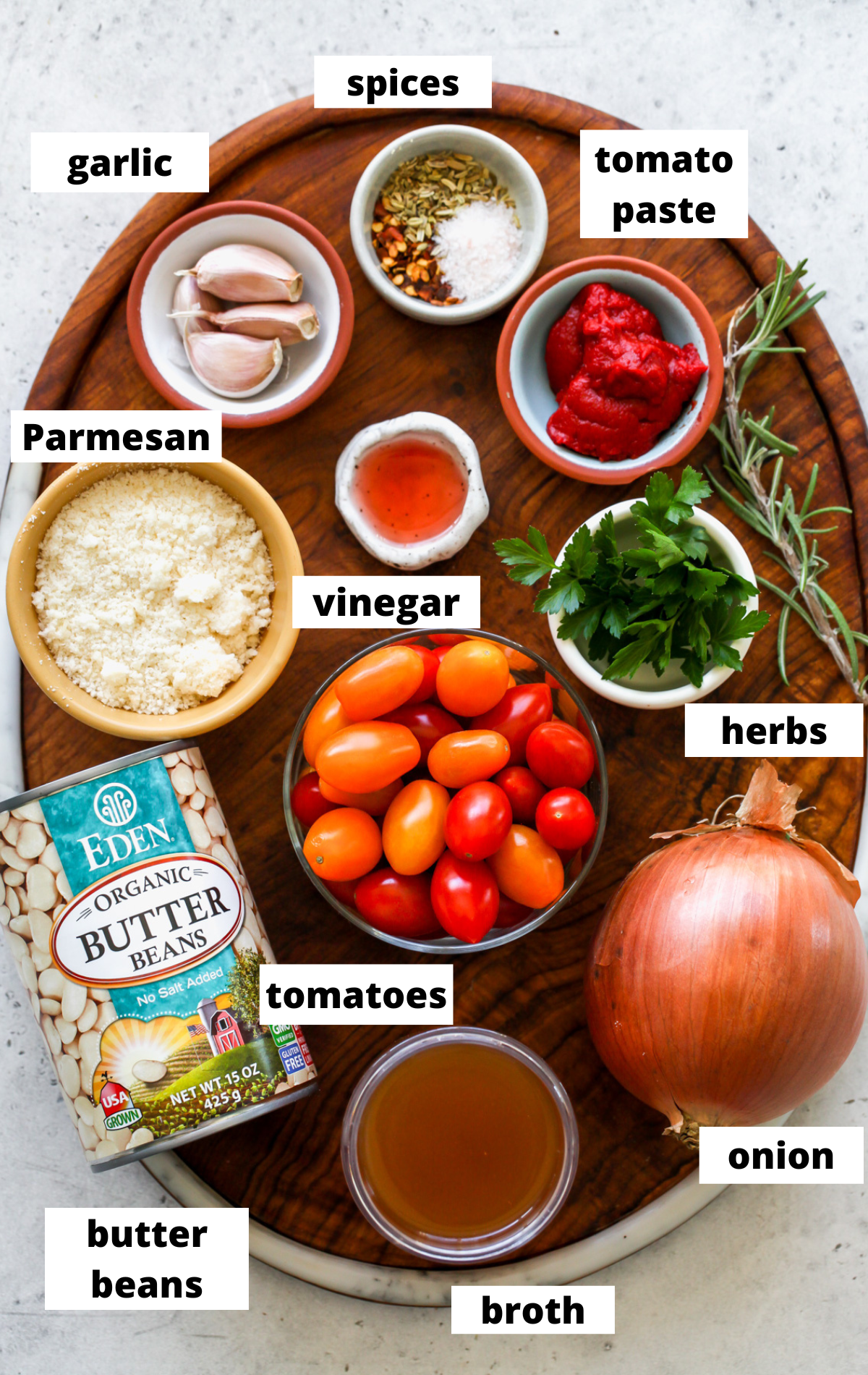 Recipe ingredients arranged in separate bowls with labels on a wooden serving board.