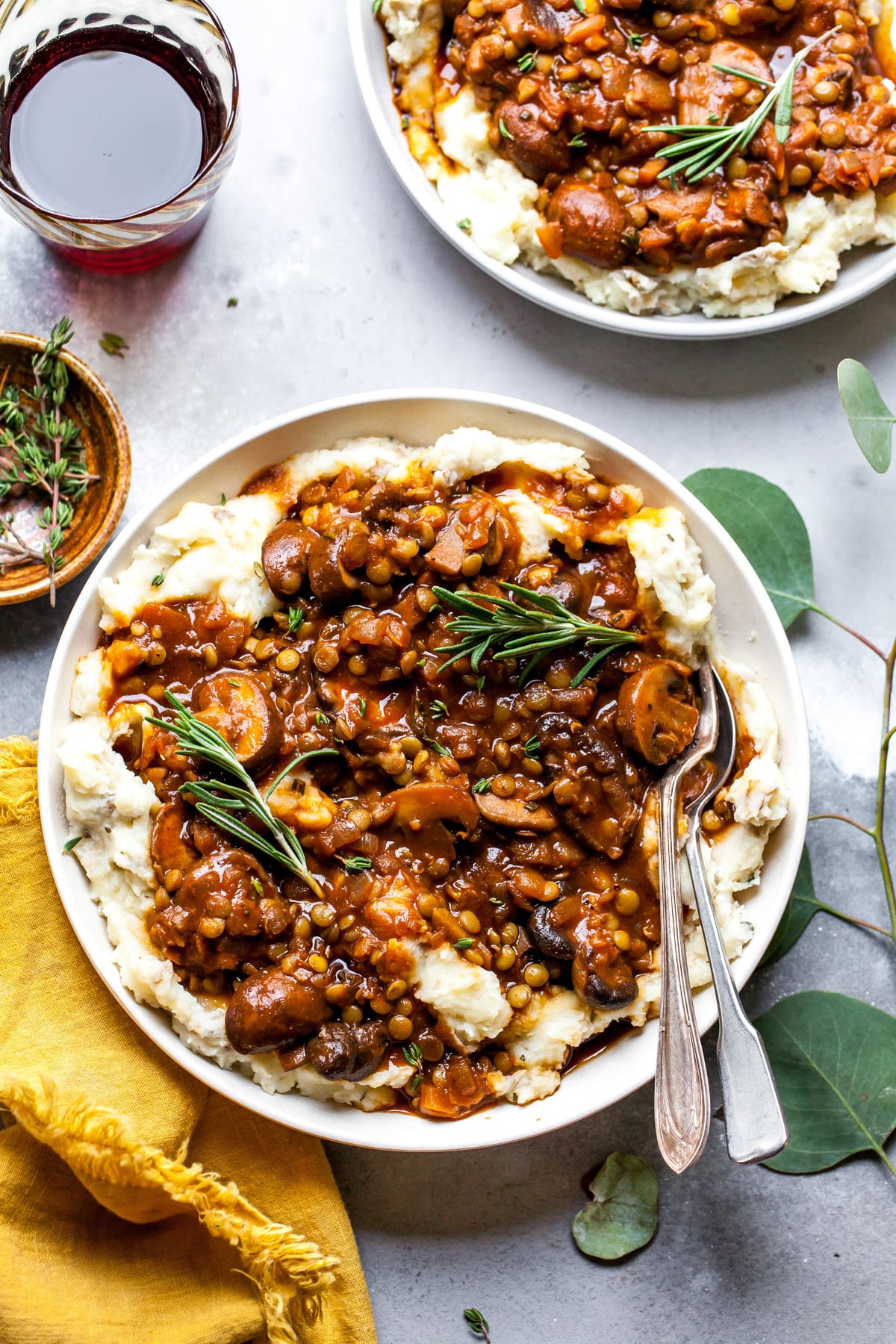 Lentil and mushroom stew being served over potato-parsnip mash in a white bowl.