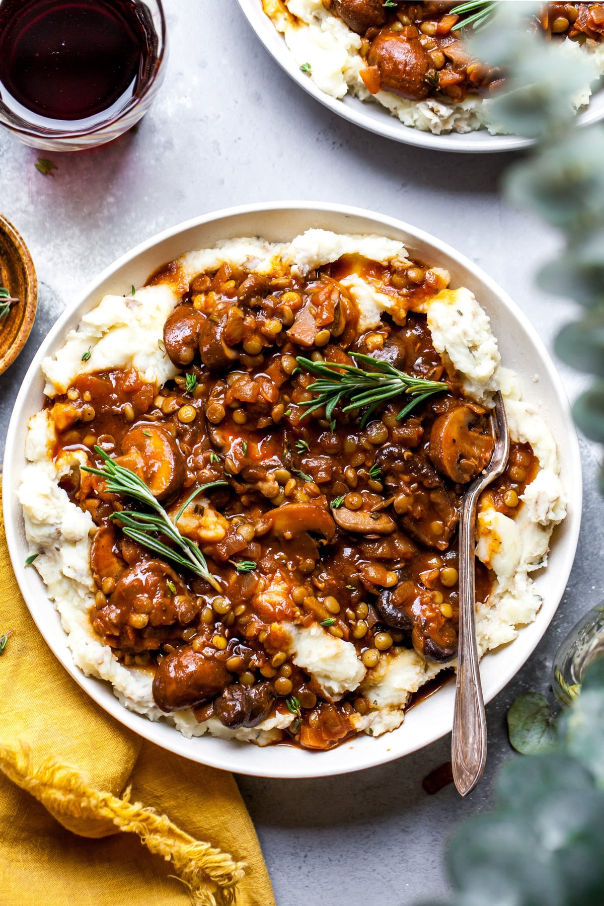 Stewed mushroom and lentil mixture served over mashed potatoes and parsnips in a white bowl.