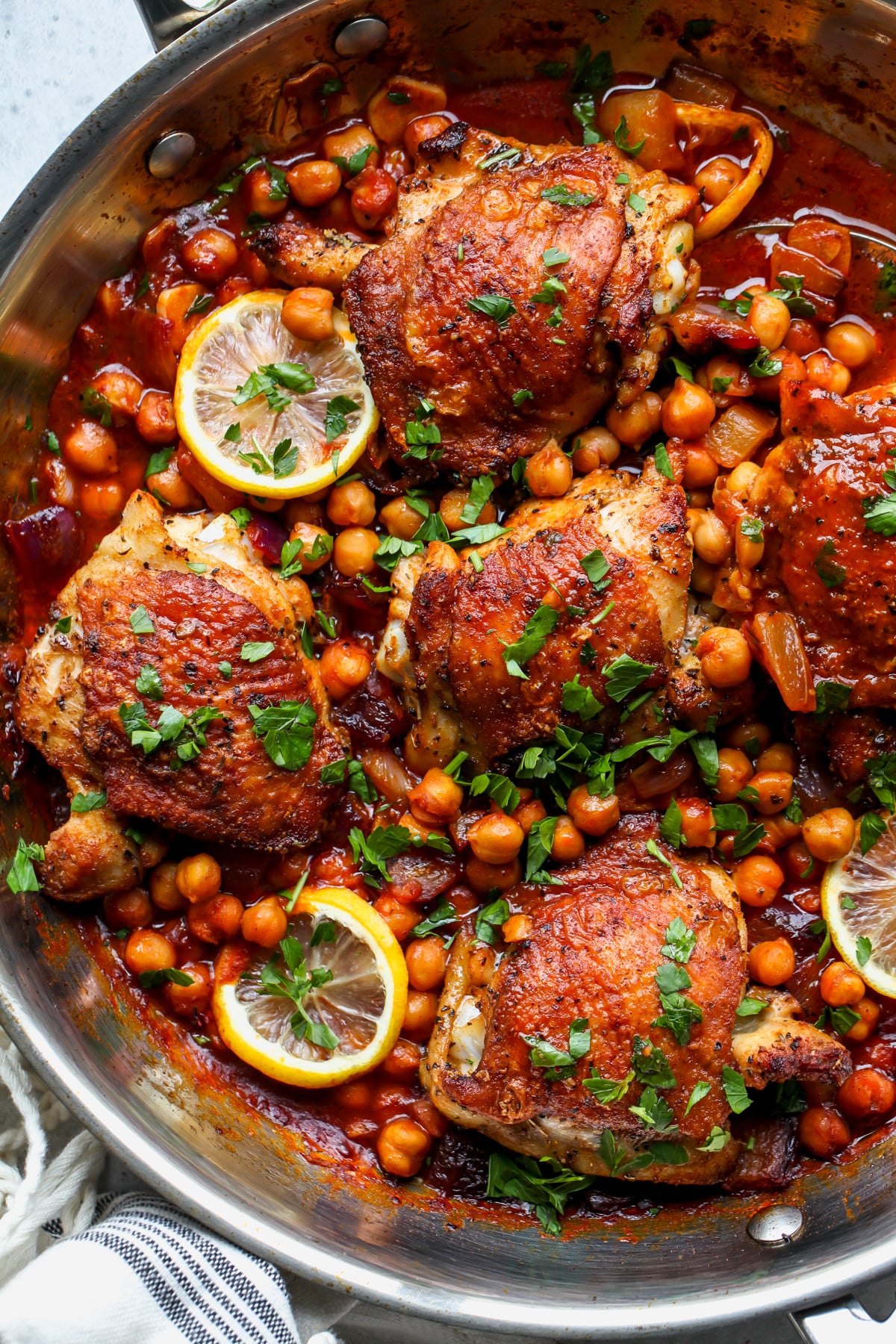 Moroccan chicken and chickpeas topped with lemon and parsley in a sauté pan.