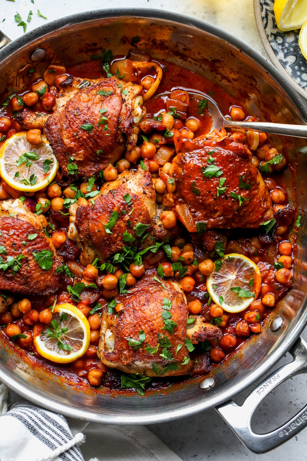 A sauté pan filled with Moroccan-spiced chicken thighs and chickpeas.