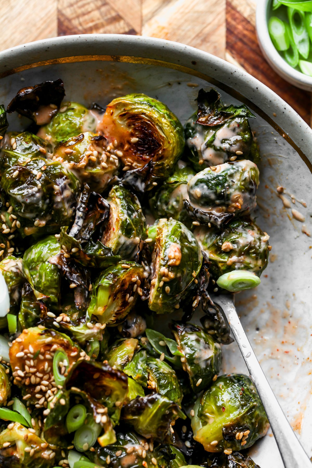 A spoon scooping up a serving of Brussels sprouts out of a serving bowl.