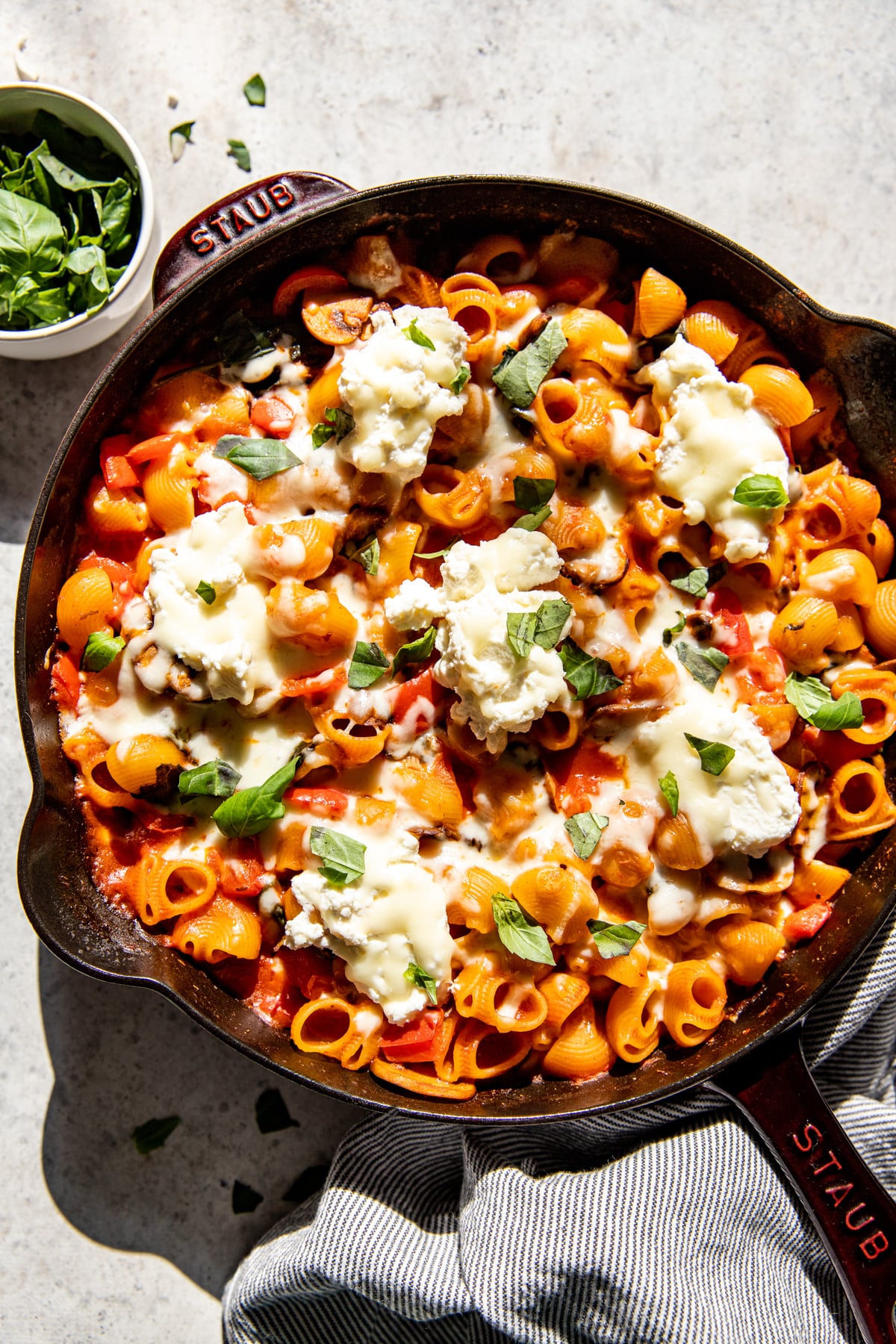 Vegetable Pasta Bake styled in a cast iron skilled topped with fresh basil.