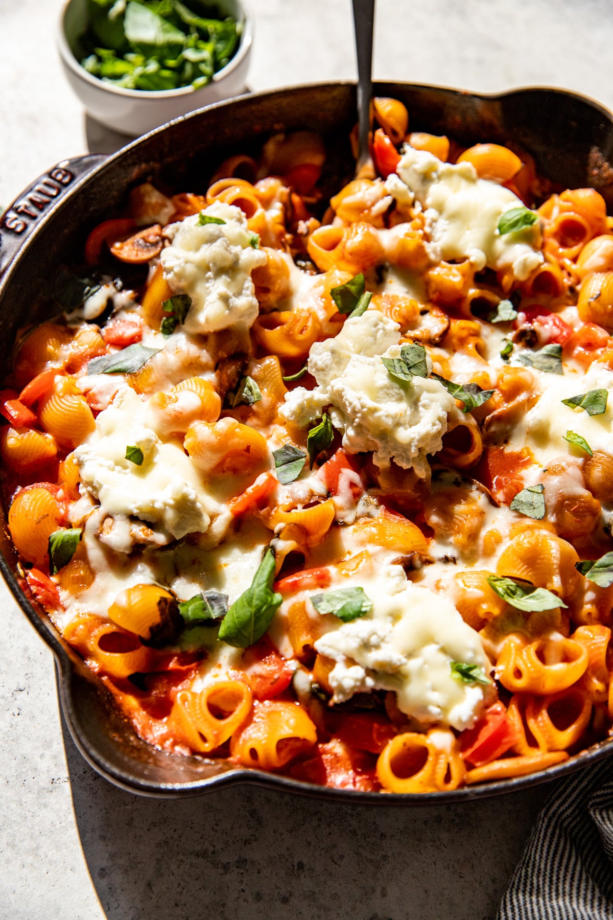 Vegetable Pasta Bake topped with basil styled in a black cast iron skillet.