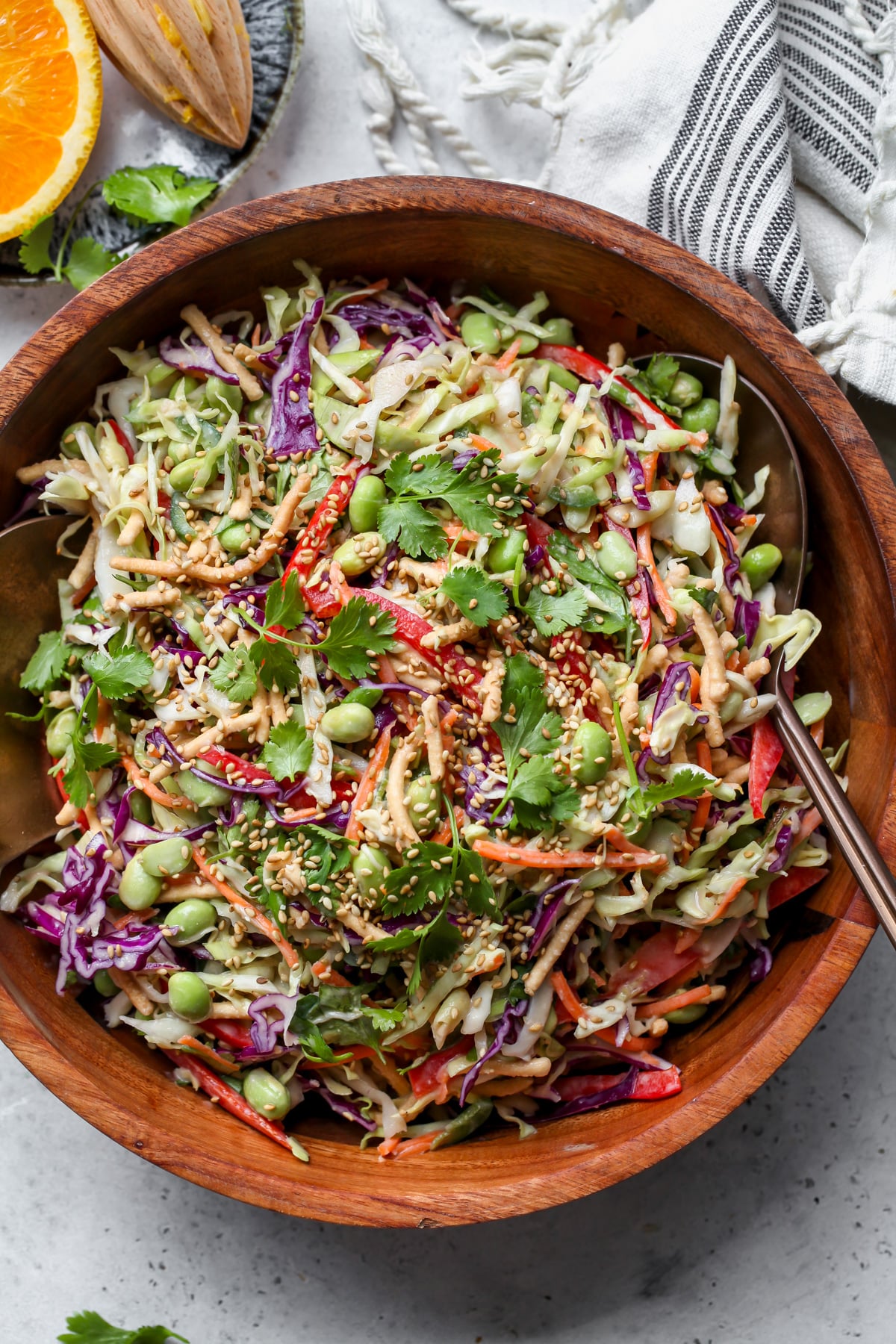 Chopped asian salad styled in a wooden serving bowl with utensils resting on each side.