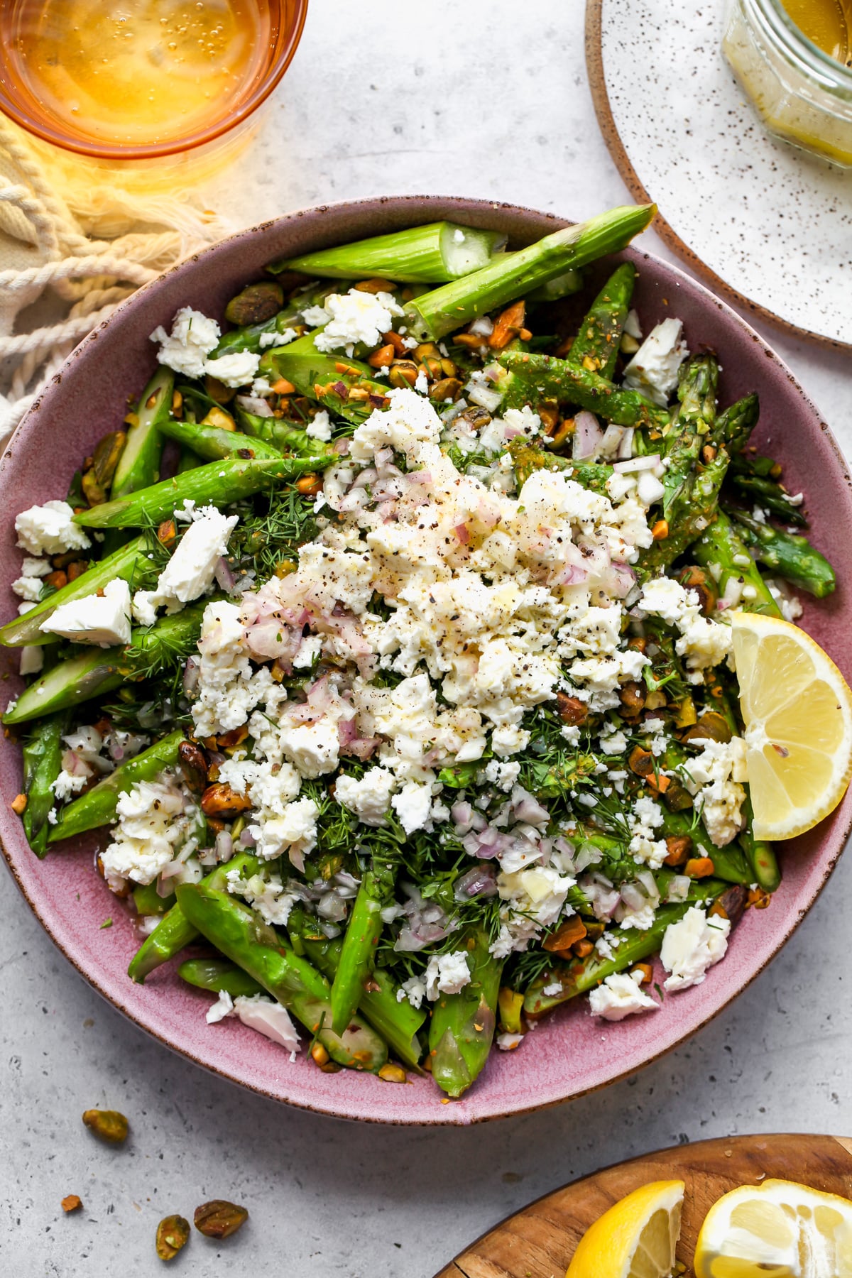Asparagus salad recipe ingredients being assembled in a pink serving bowl.