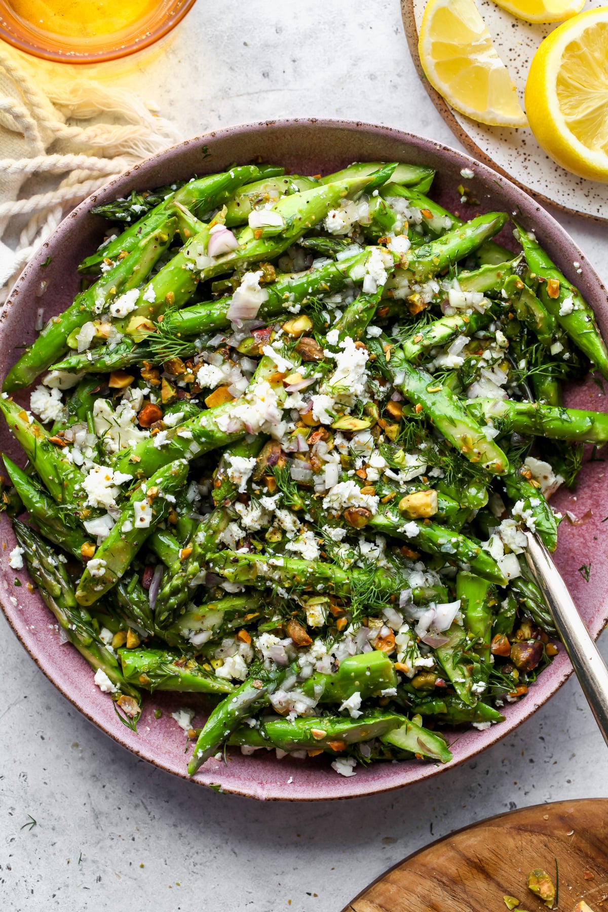 Asparagus and Feta Salad styled in a pink bowl on a grey surface.