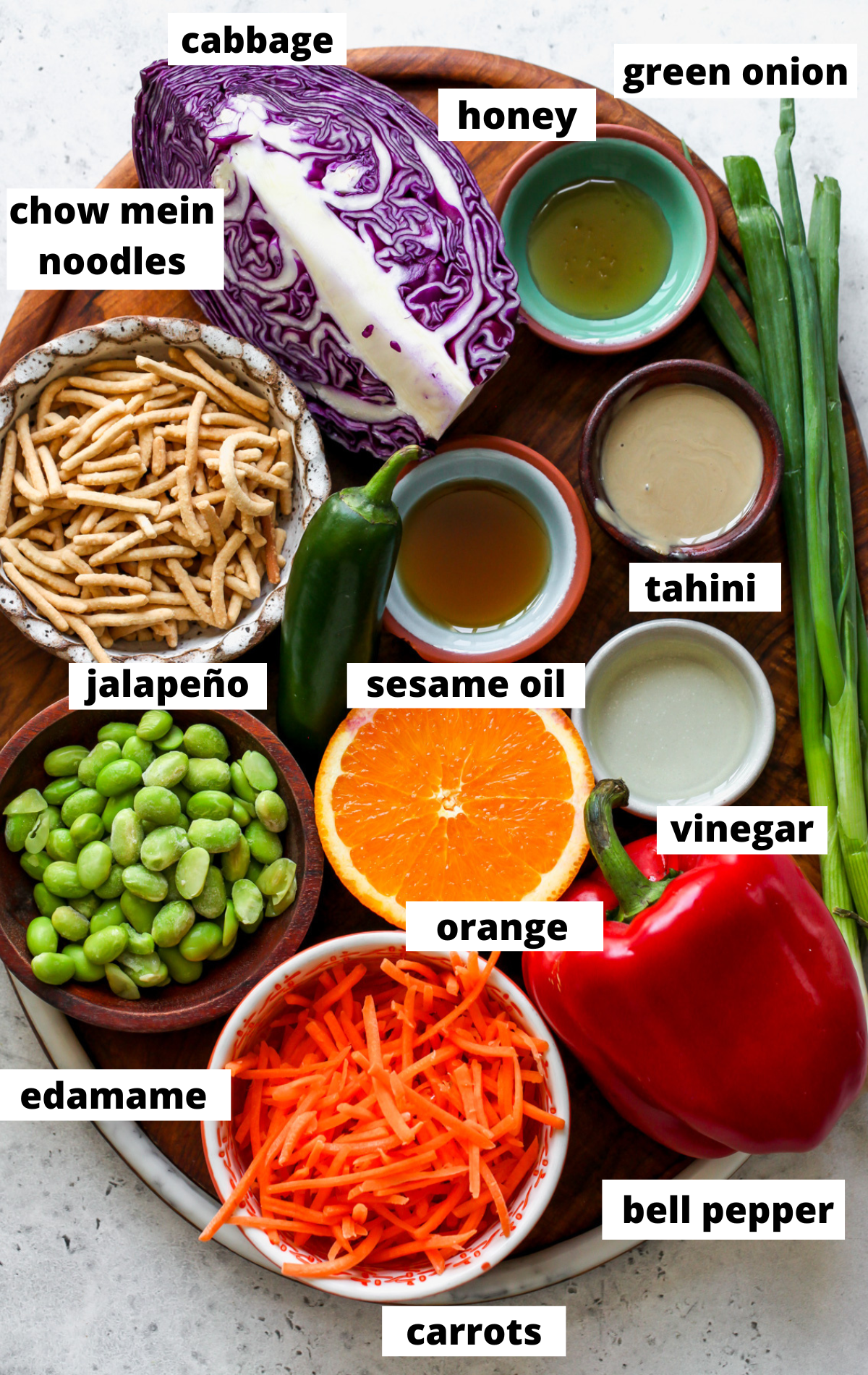 Recipe ingredients in separate bowls arranged on a wooden platter with labels.