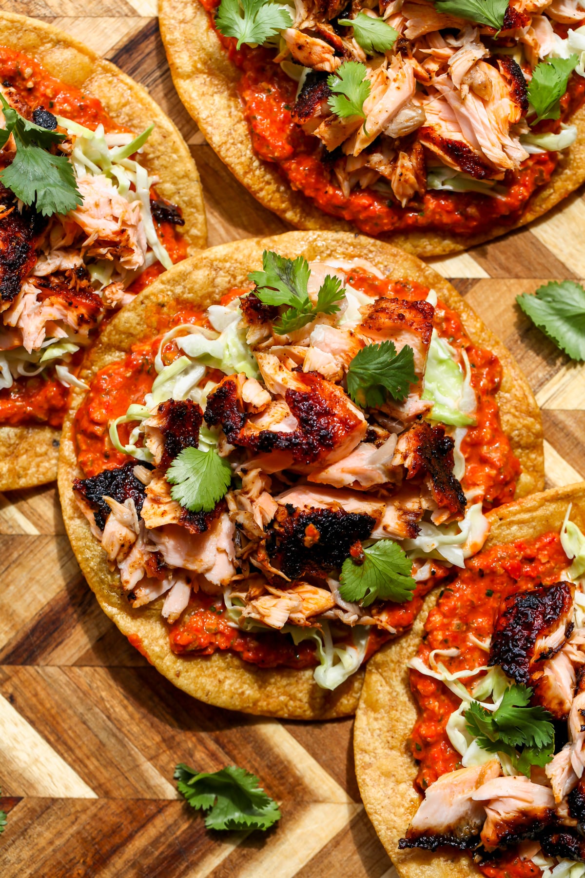 Salmon tostadas with pepita salsa assembled on a cutting board.
