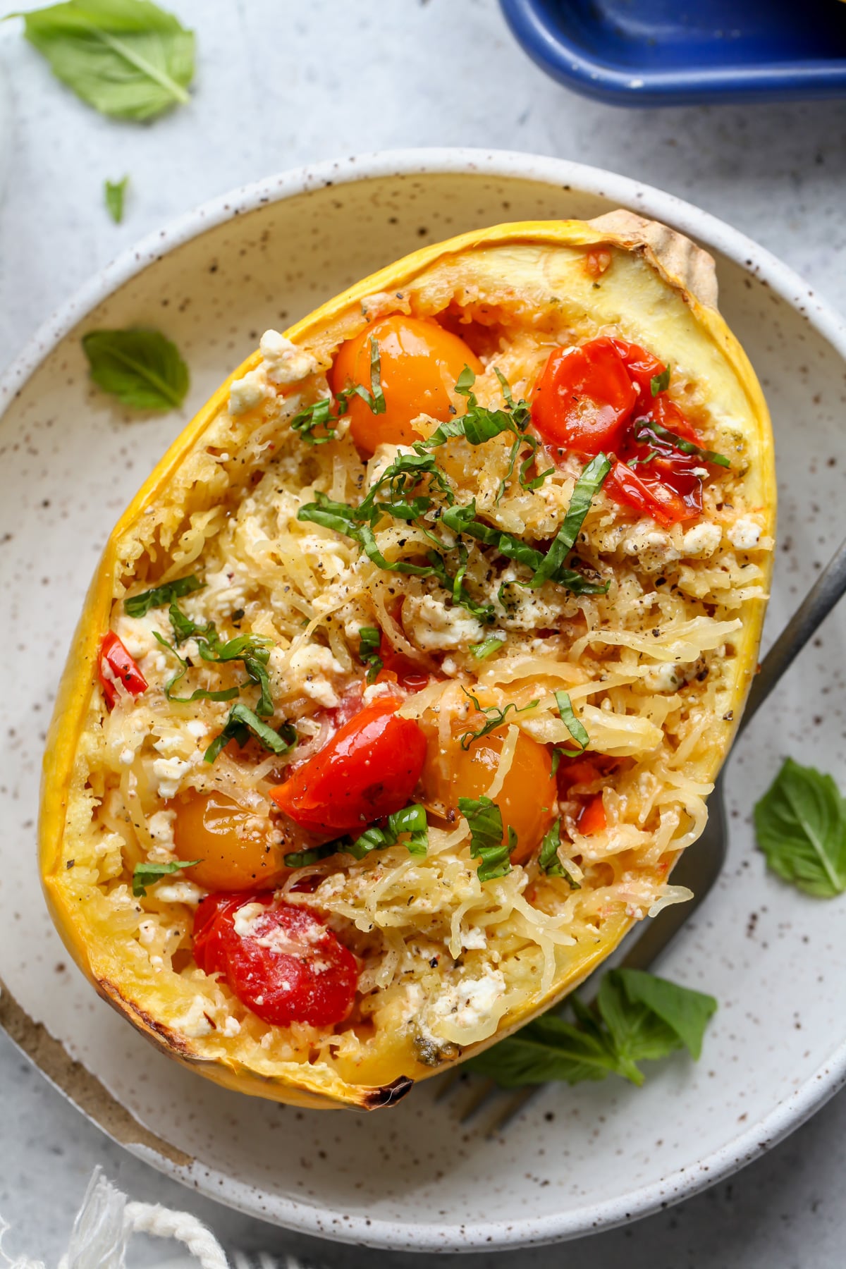 Baked feta spaghetti squash on a white plate with a fork resting on the right side.