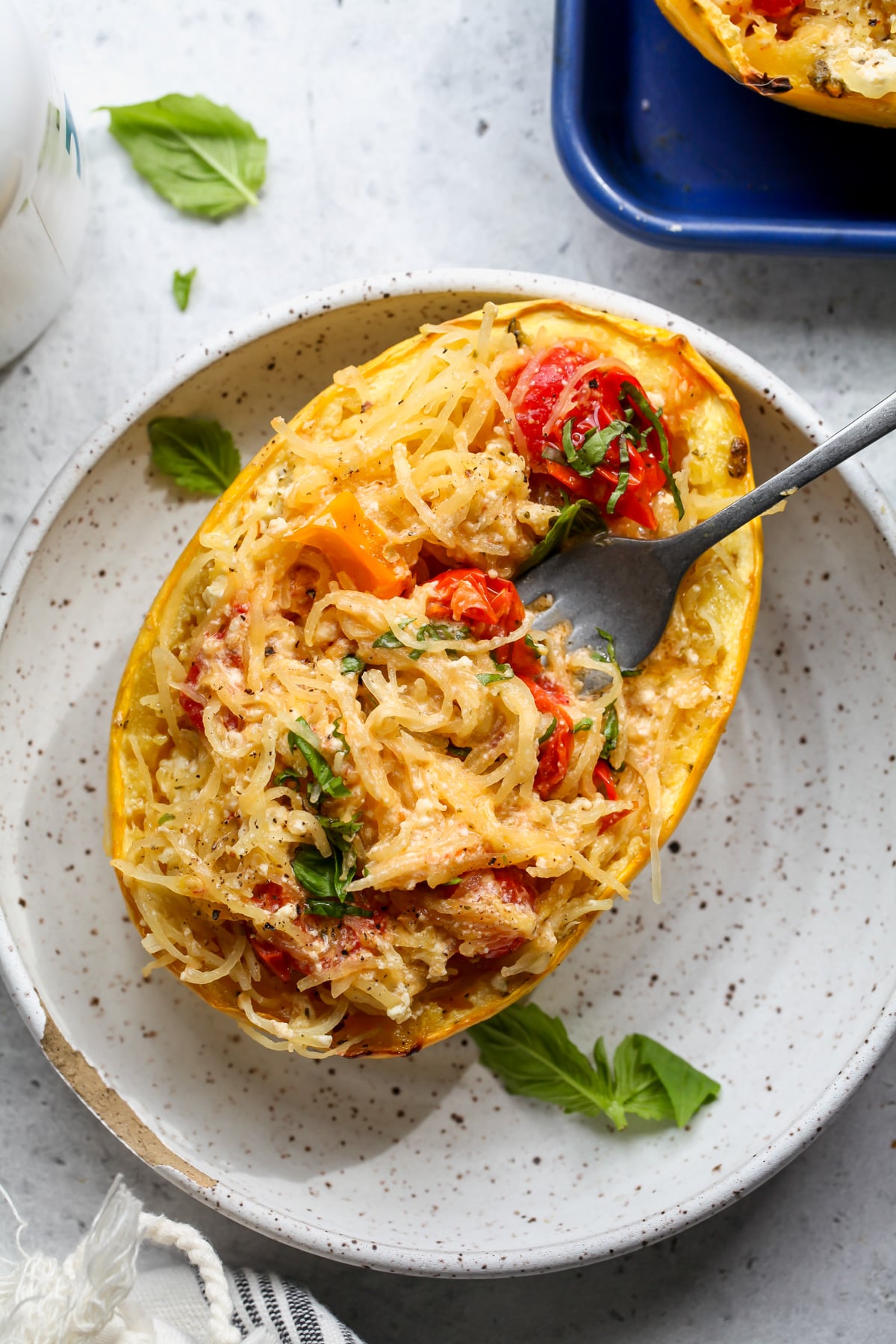 Spaghetti squash being mixed with feta and tomato mixture until it's creamy and combined.