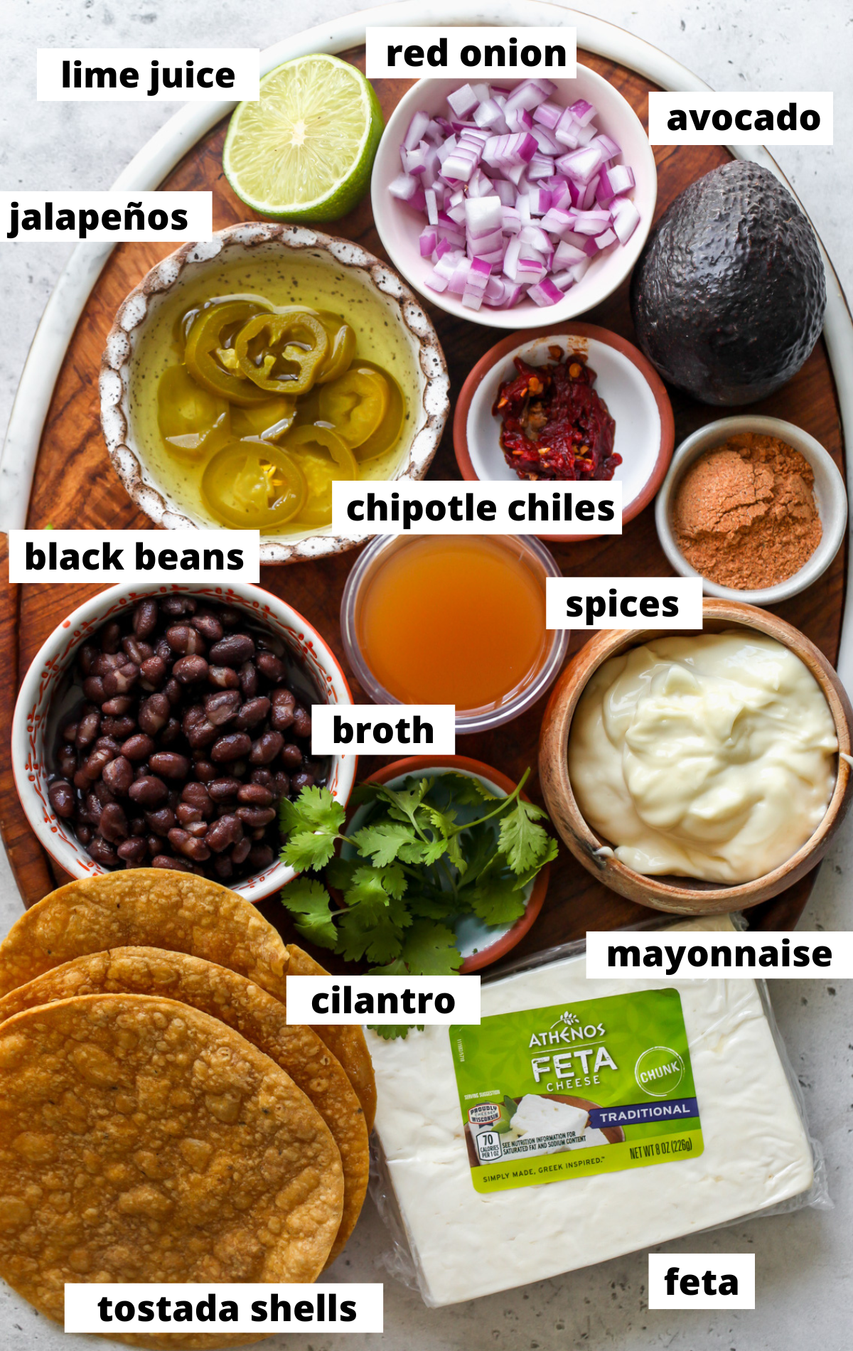 Recipe ingredients in separate bowls arranged on a wooden serving platter with labels.
