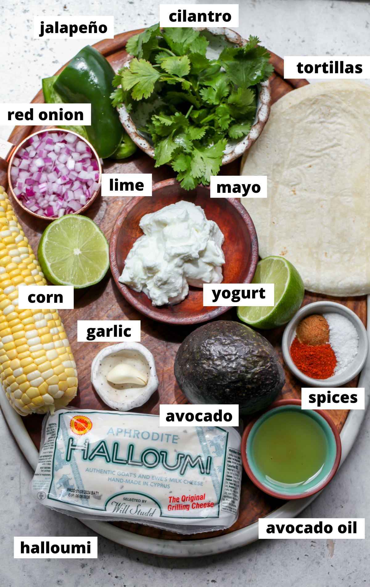 Recipe ingredients in separate bowls arranged on a wooden platter with labels.