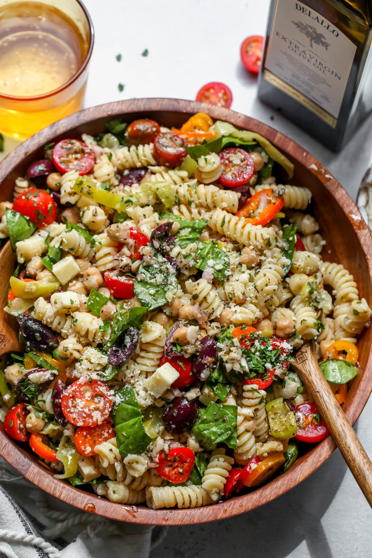 Italian Pasta Salad (Vegetarian) being styled next to a bottle of DeLallo extra-virgin olive oil.