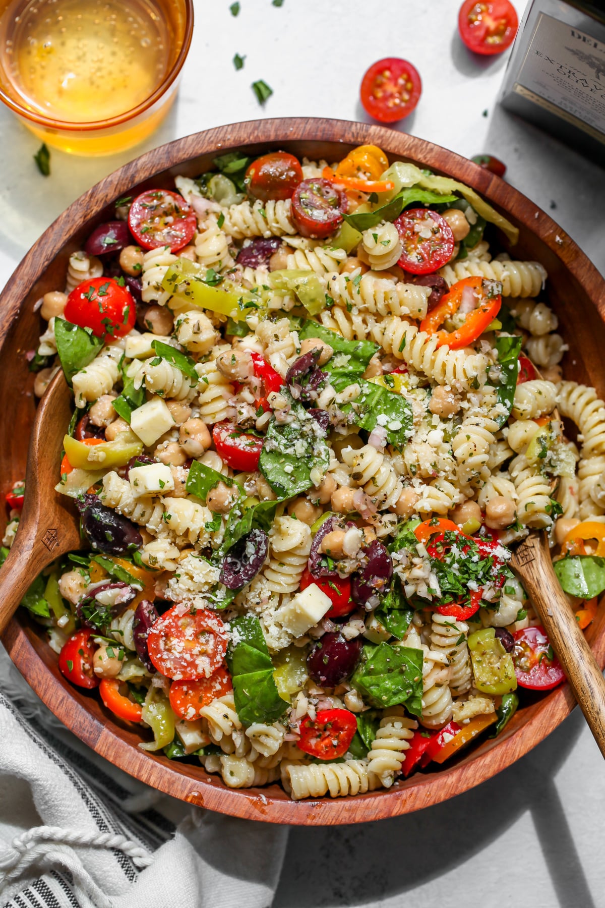 Italian pasta salad styled in a wooden serving bowl with two spoons resting on each side.