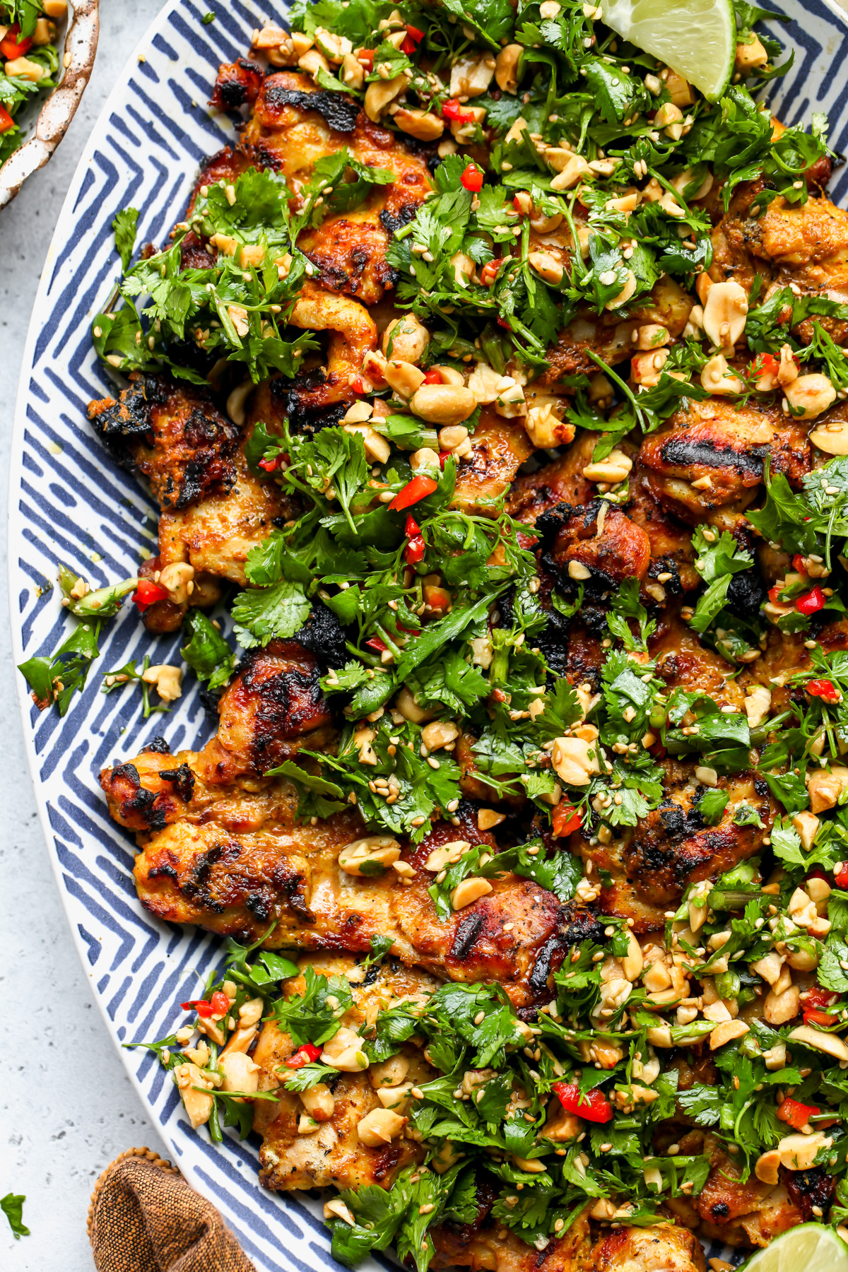 Curried chicken thighs topped with cilantro-peanut salad styled on a gray surface.