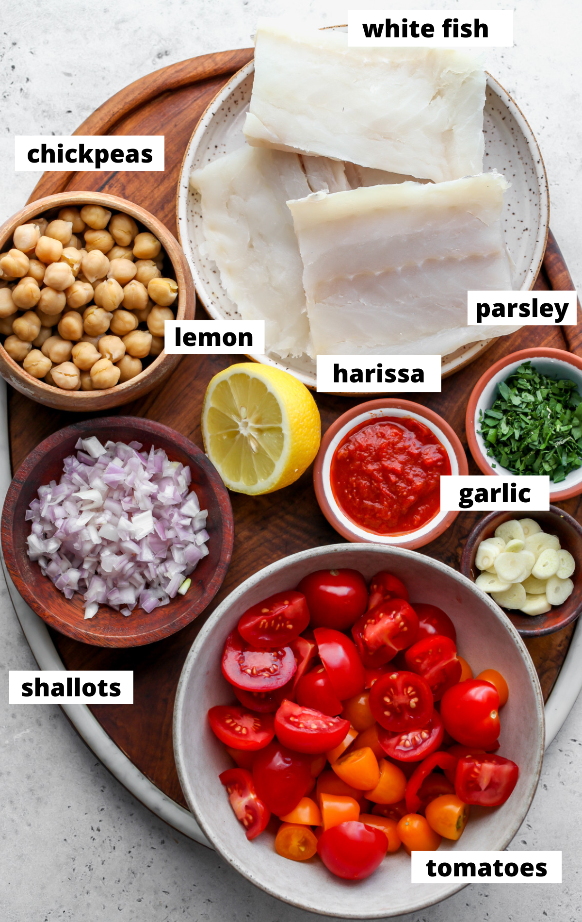 Recipe ingredients in separate bowls with labels on a wooden tray.