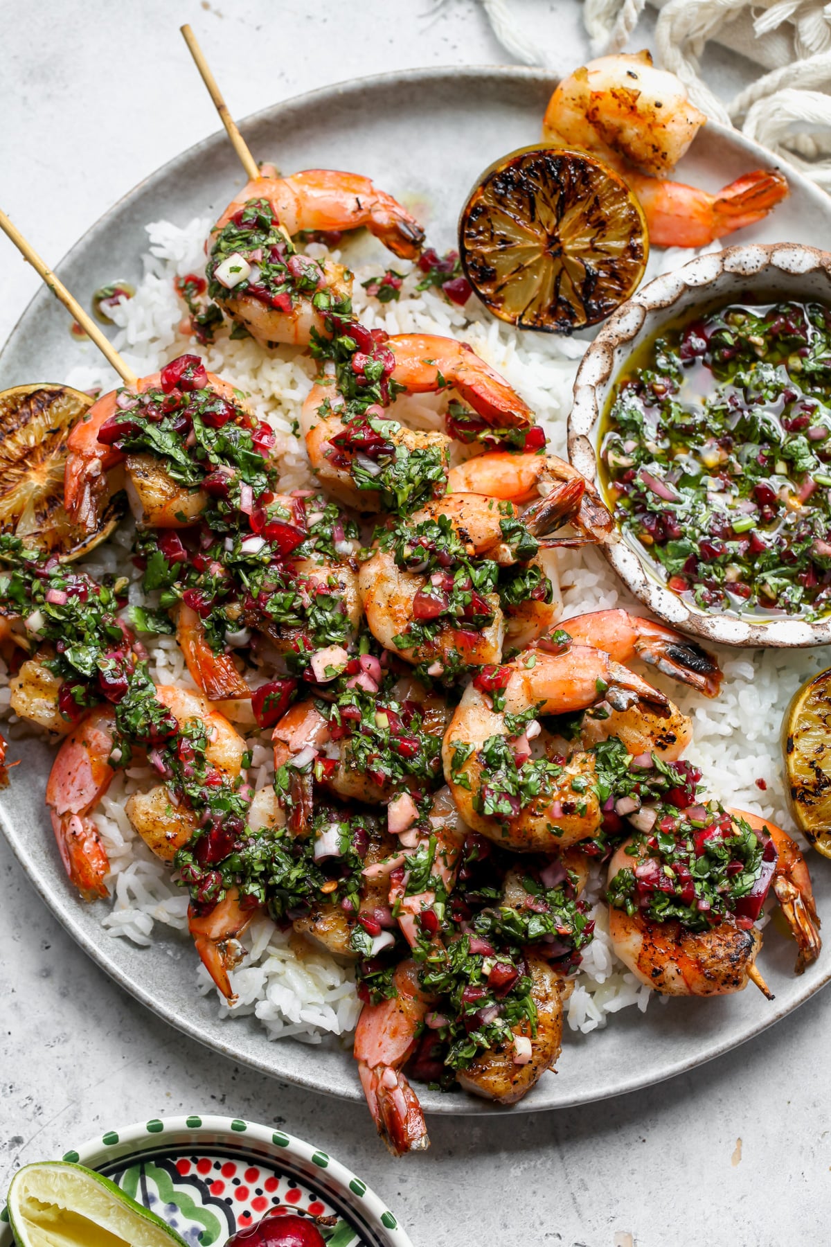 Shrimp skewers over rice with cherry chimichurri sauce spooned overtop.