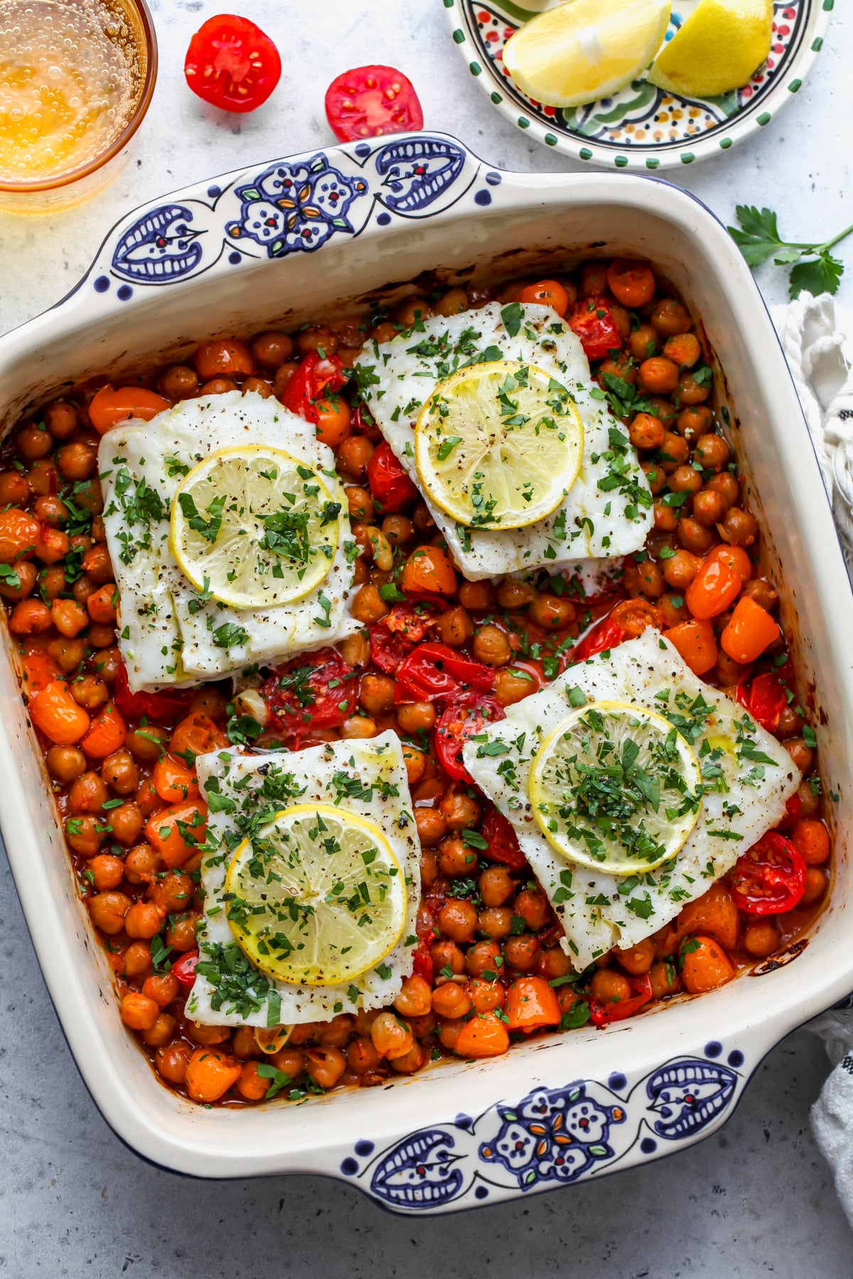 Spicy Moroccan baked fish styled in a baking dish topped with lemon slices and chopped parsley.