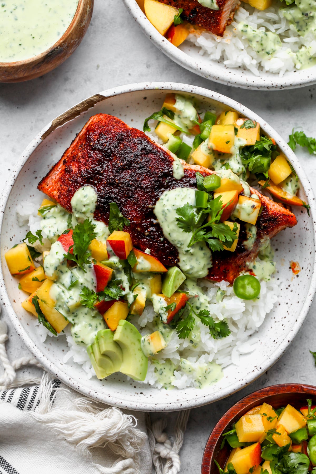 BBQ salmon bowl with cilantro sauce styled in a white speckled bowl on a white surface.