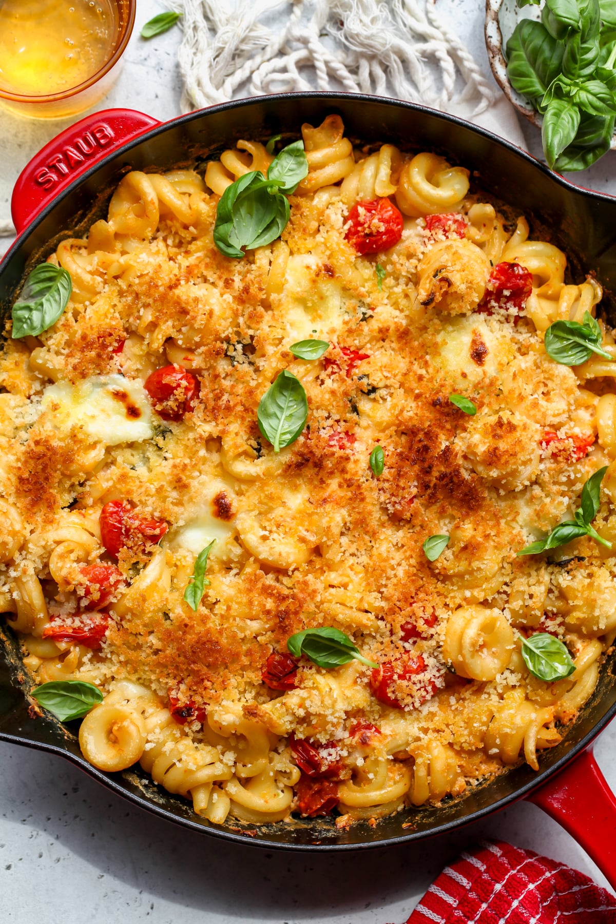 Caprese mac and cheese styled in a black and red cast iron skillet topped with fresh basil.
