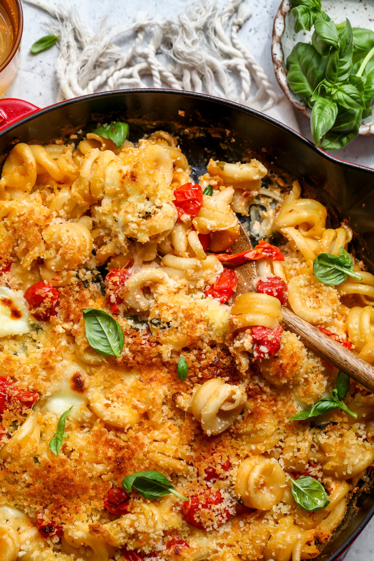Caprese mac and cheese styled in a cast iron skillet with a spoon resting on the right side.