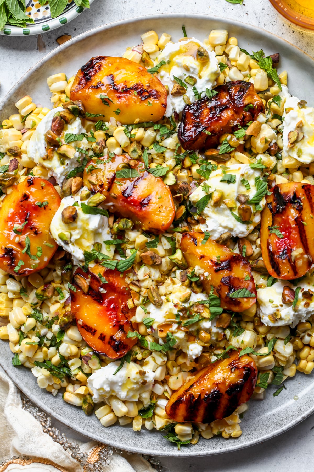 Peach Burrata Salad on a platter topped with pistachios and herbs.
