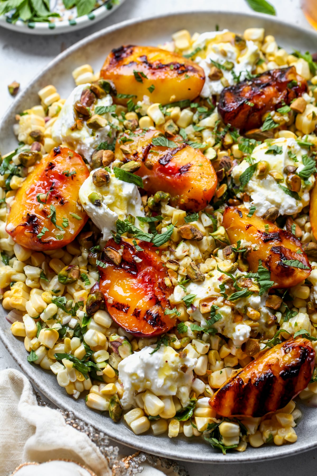 Peach and Burrata Salad with hot honey dressing assembled on a gray round platter.