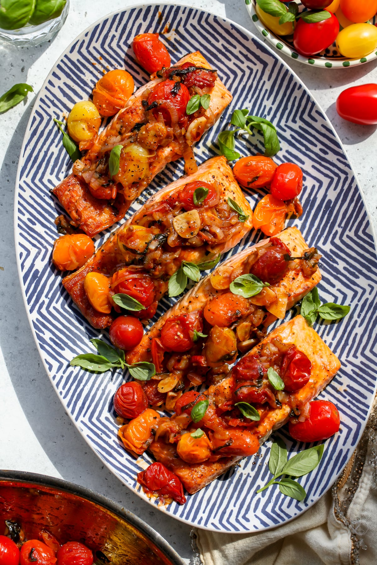Broiled salmon with balsamic tomatoes arranged on a blue and white platter.
