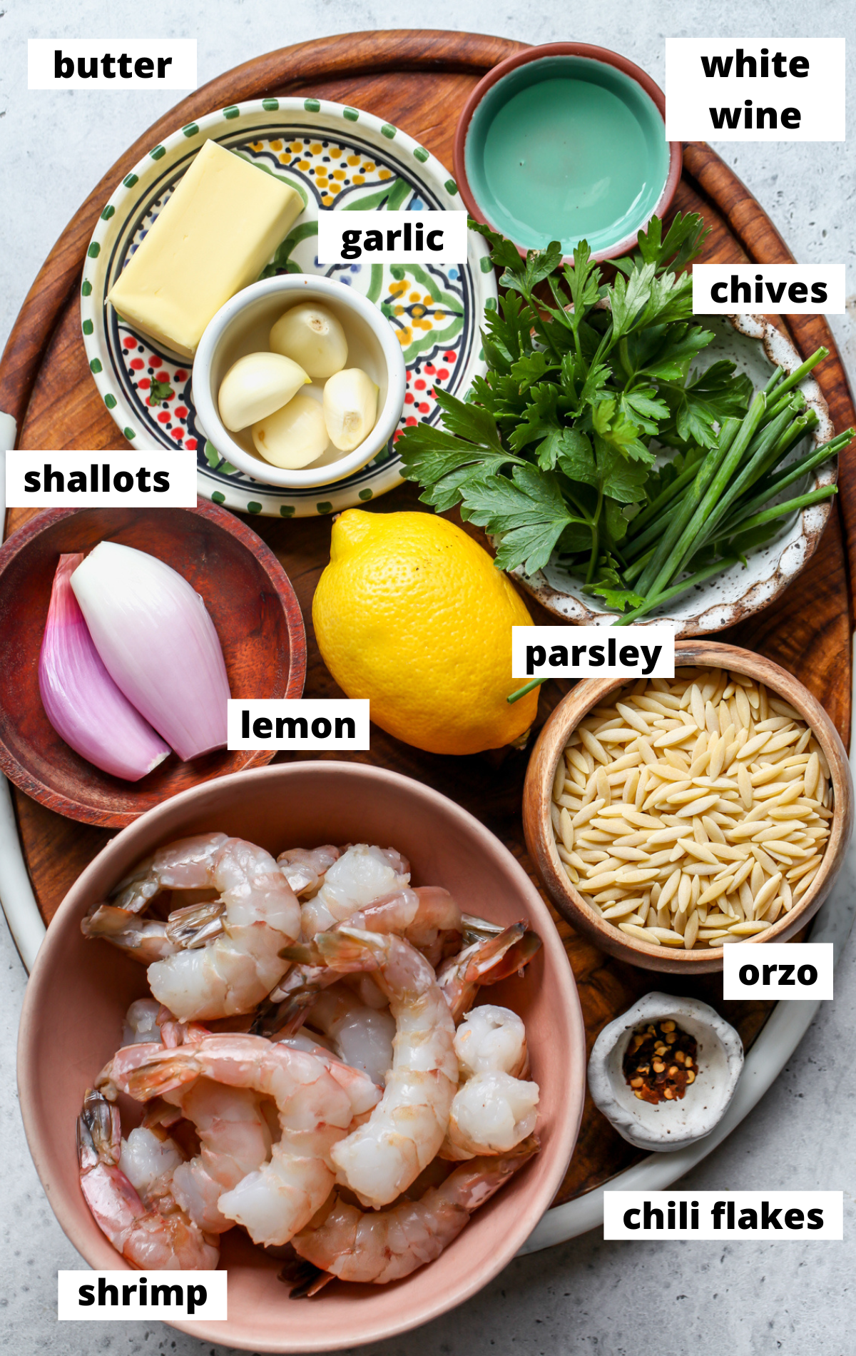 Recipe ingredients in separate bowls arranged on a wooden platter with labels.