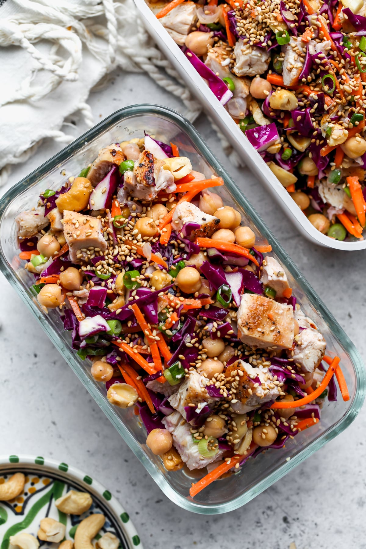Two Tupperware containers filled with chicken and chickpea salad on a gray surface.