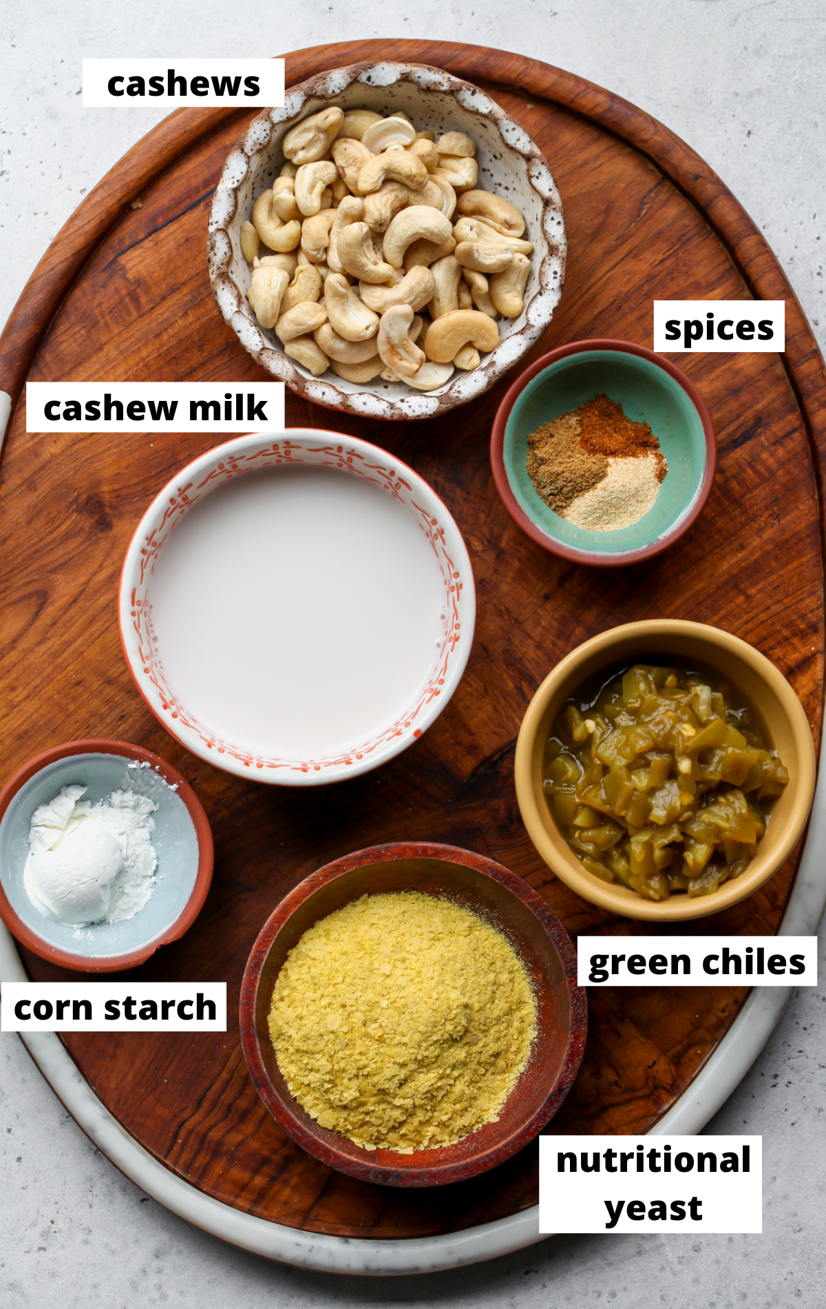 Recipe ingredients arranged on a wooden board in separate bowls with labels.