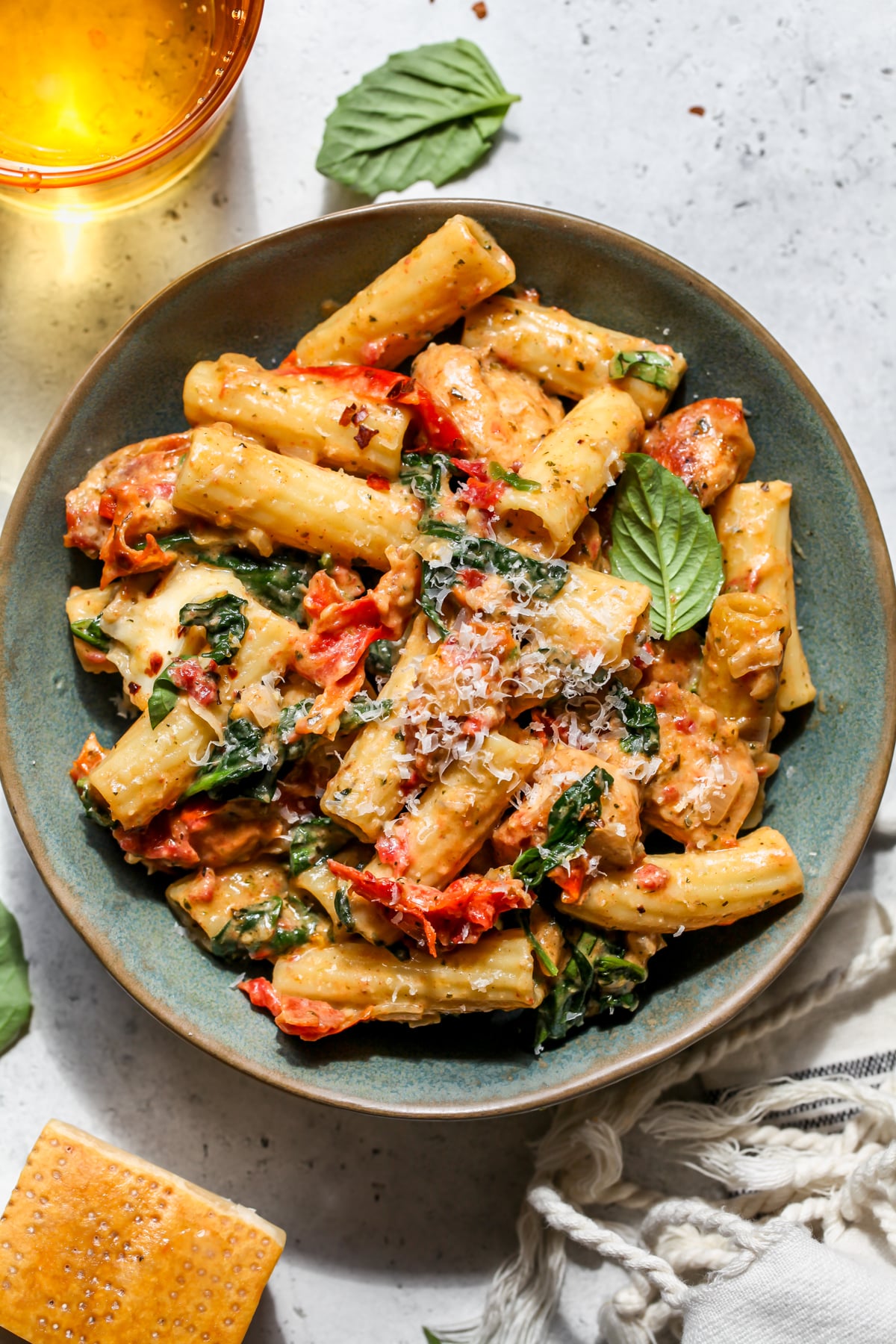 A blue bowl filled with one portion of pesto chicken pasta.