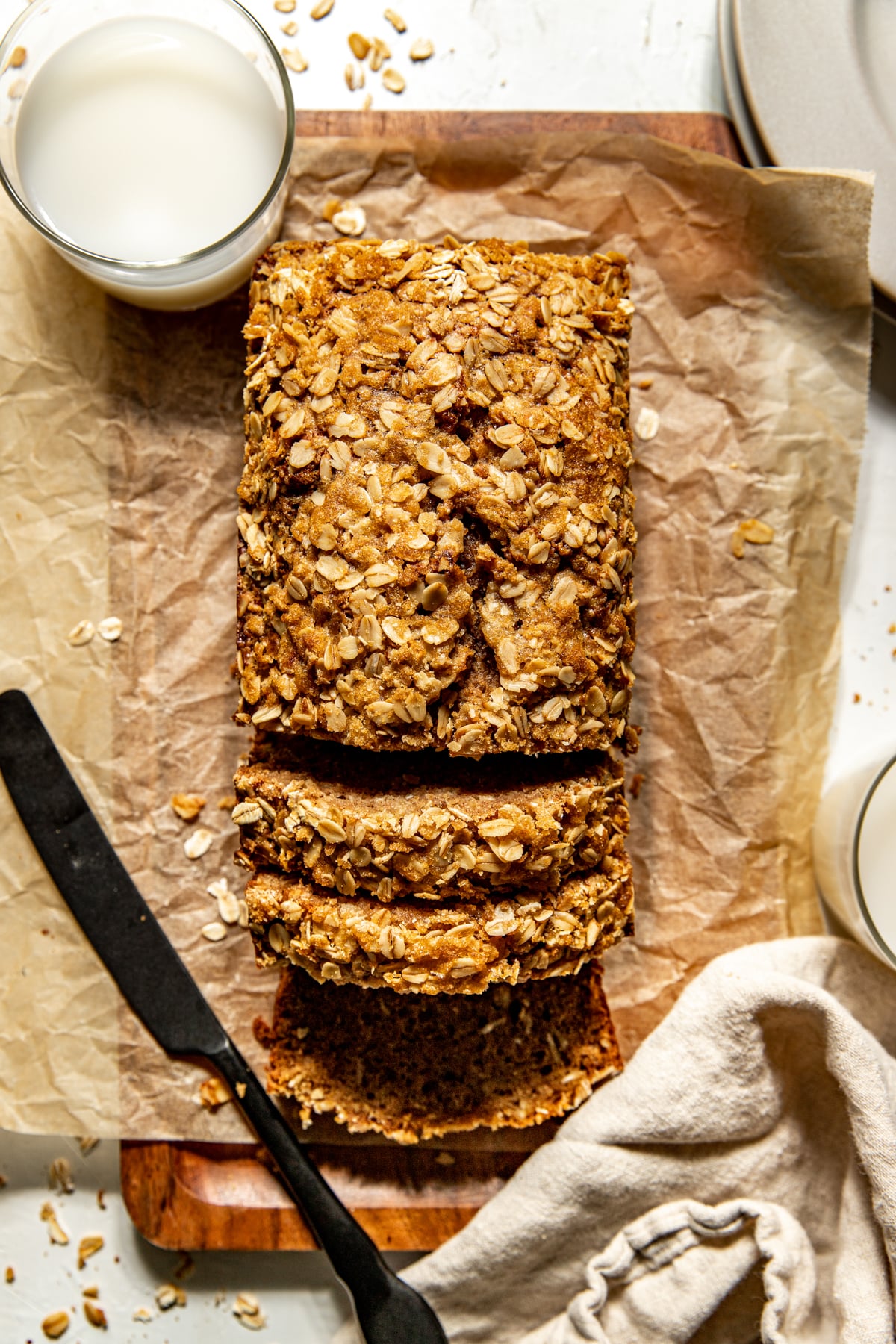 A loaf of Apple Oatmeal Bread on a cutting board being sliced into.