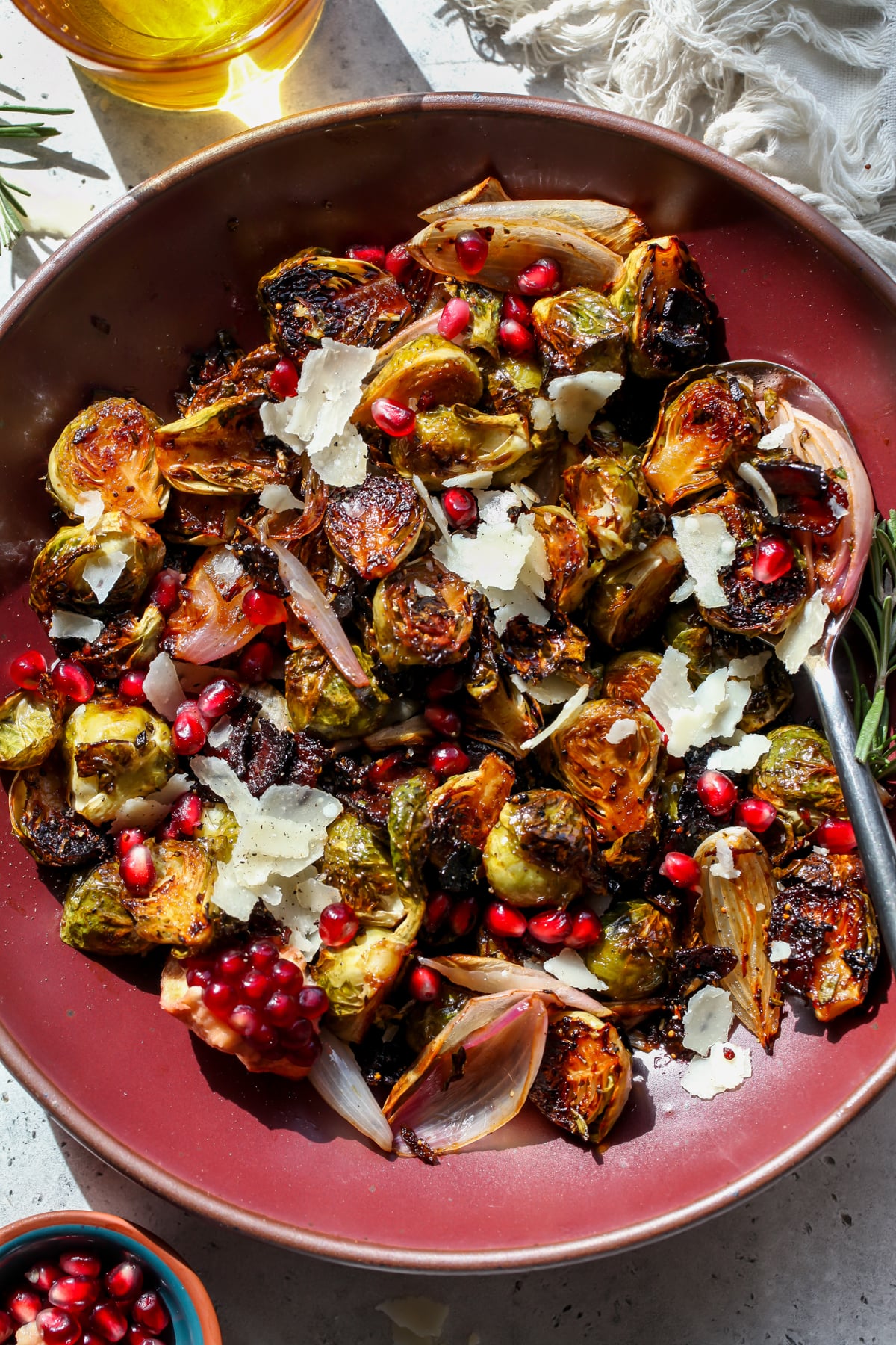 Balsamic Glazed Brussels Sprouts styled in a maroon bowl with a spoon resting on the right side.