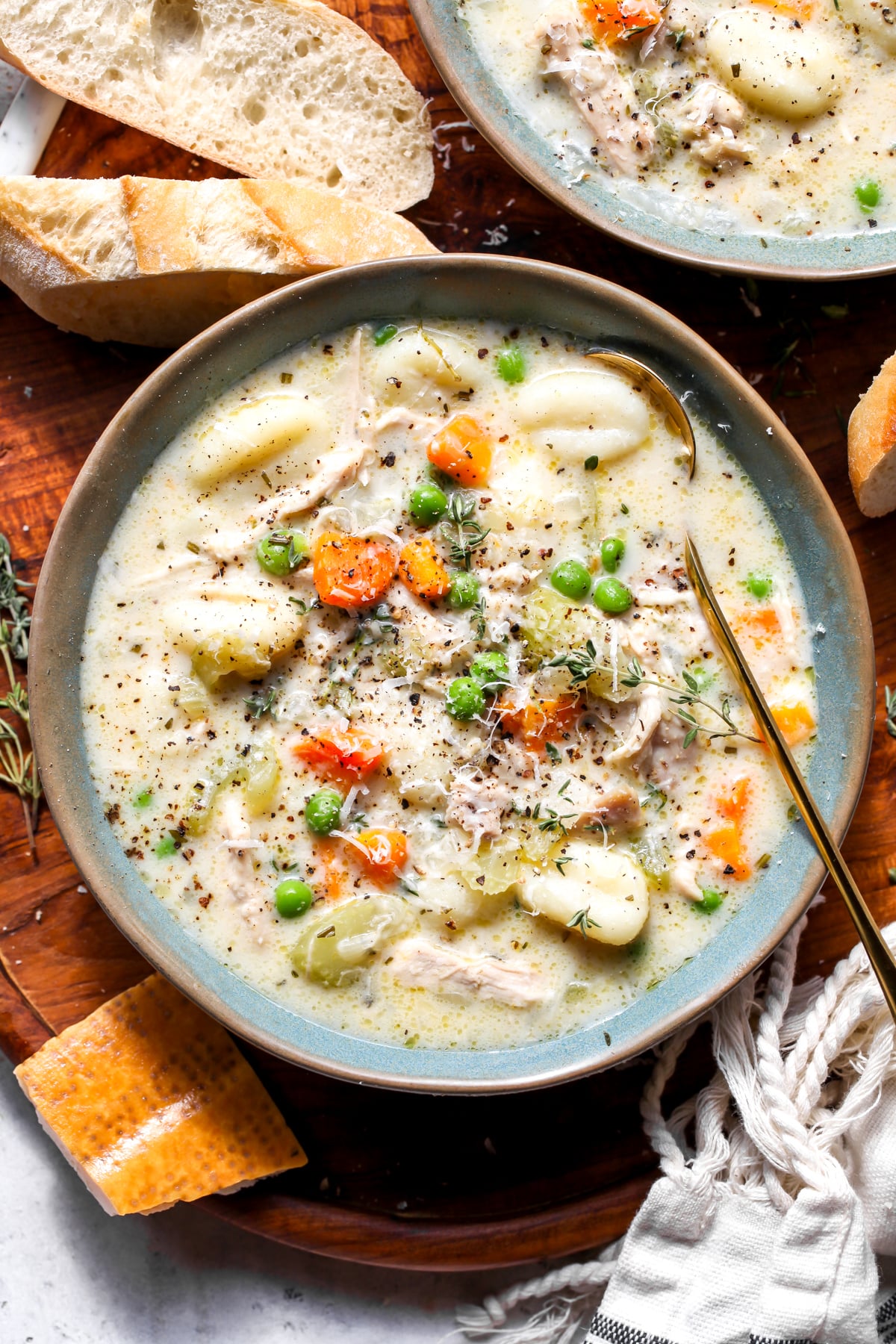 Chicken gnocchi soup styled in a blue bowl on a wooden platter.