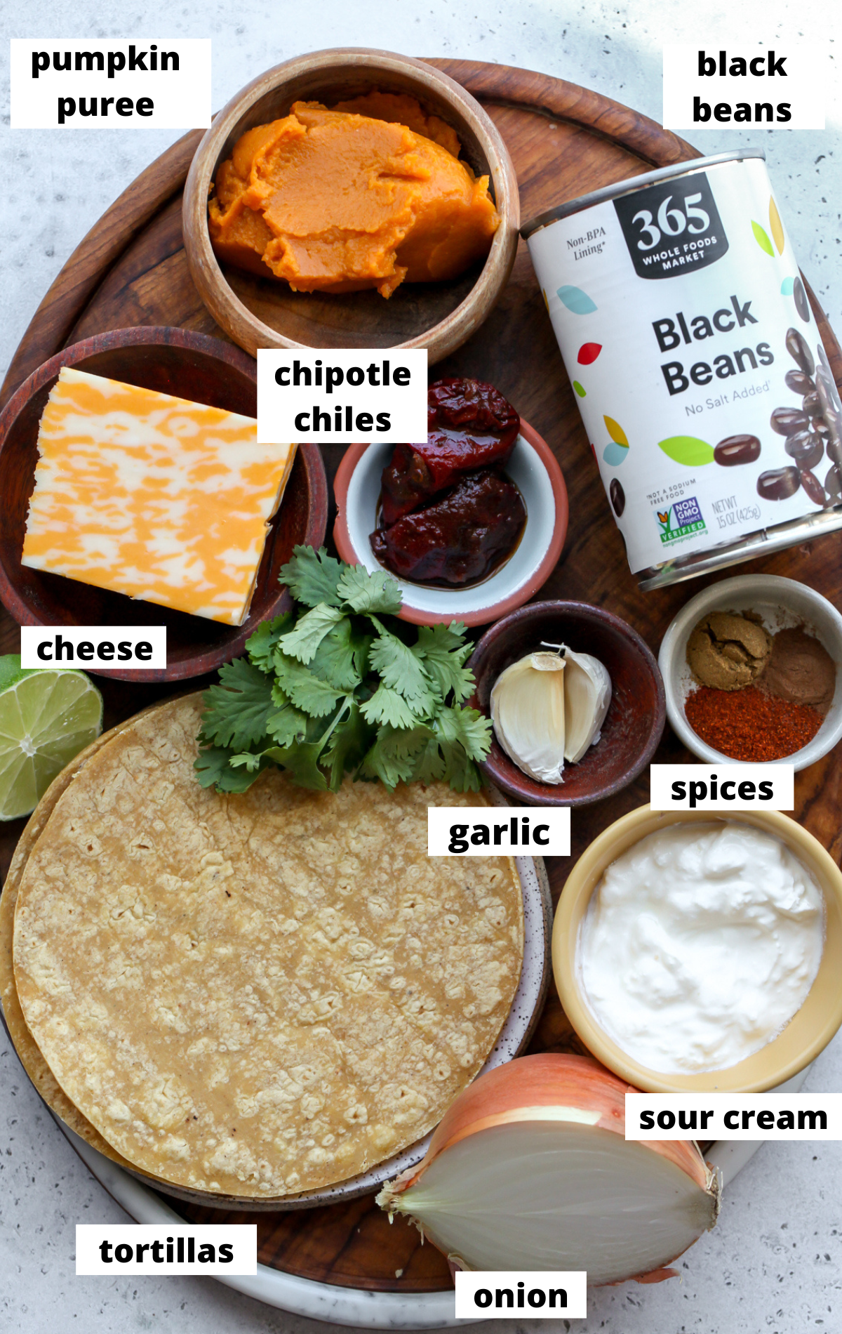 Recipe ingredients in separate bowls arranged on a wooden platter with labels.