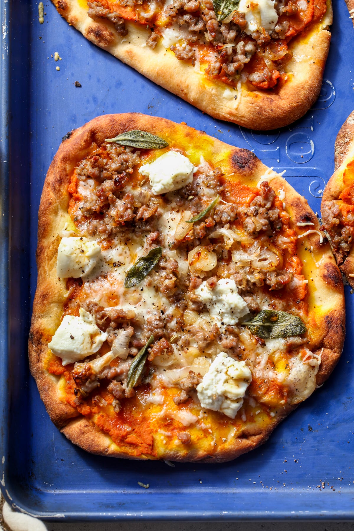 Autumn Naan Pizza arranged on a blue rimmed baking sheet.