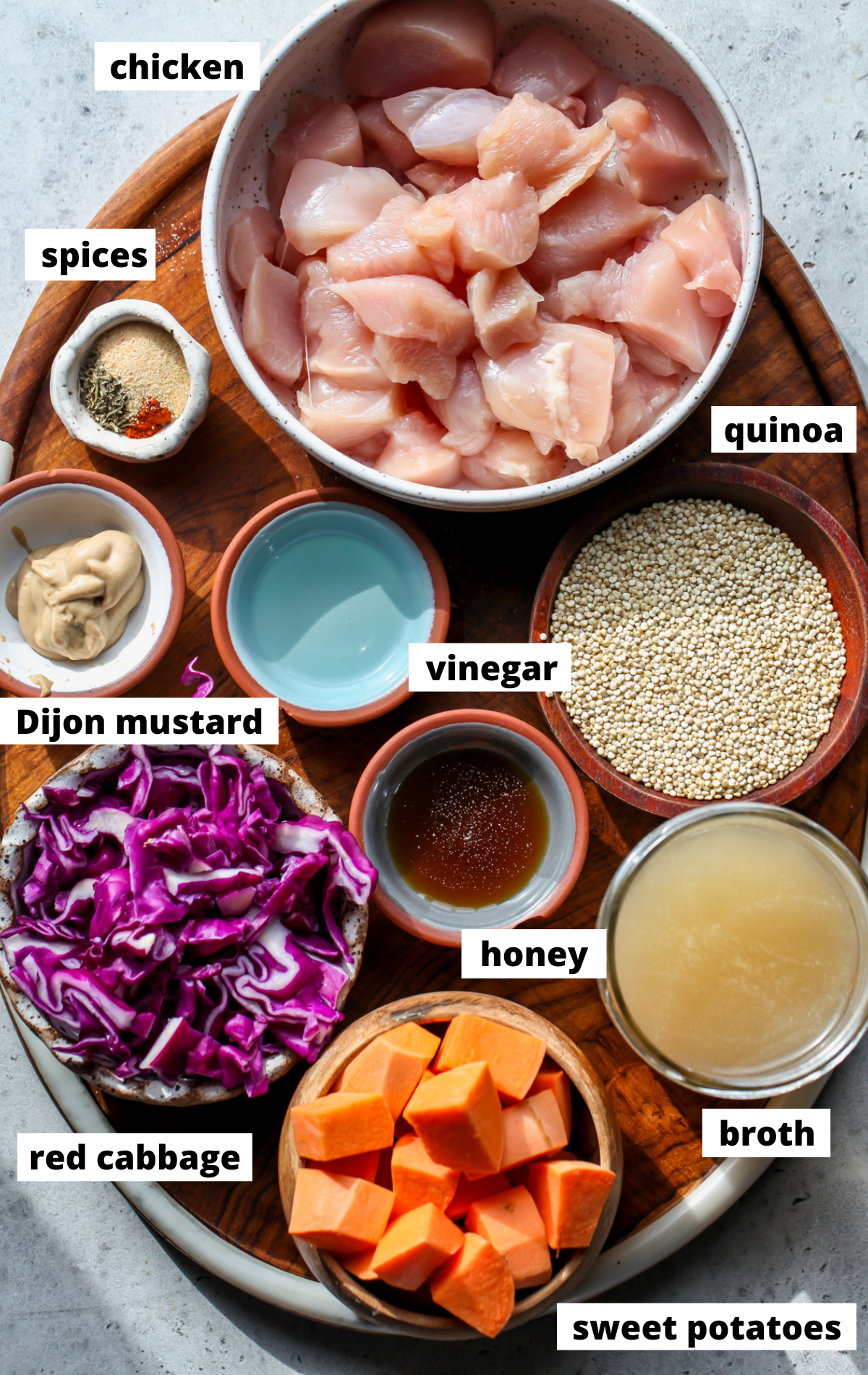 Recipe ingredients arranged on a wooden platter in bowls with labels.