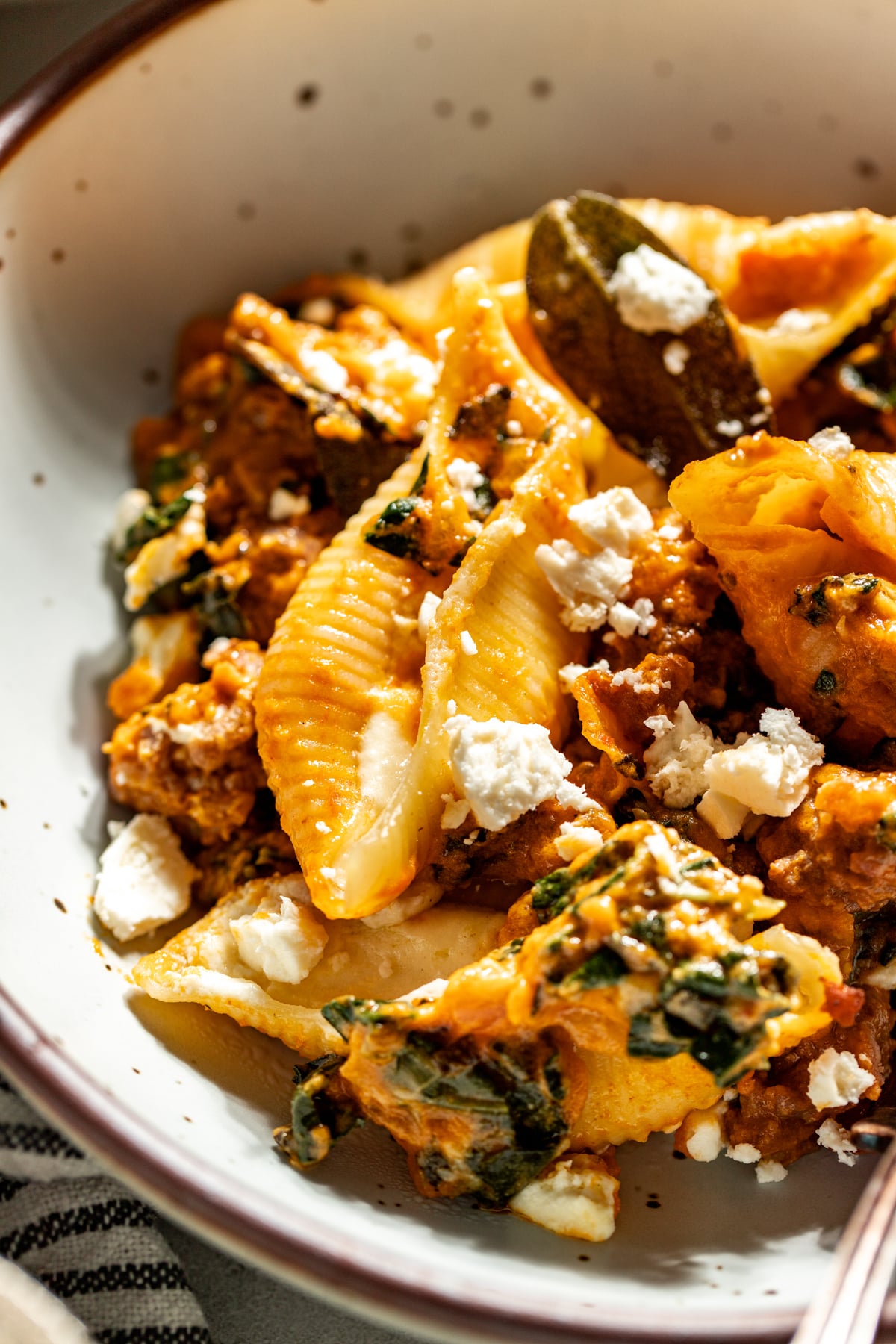 Spicy pumpkin and feta stuffed shells styled in a white pasta bowl.