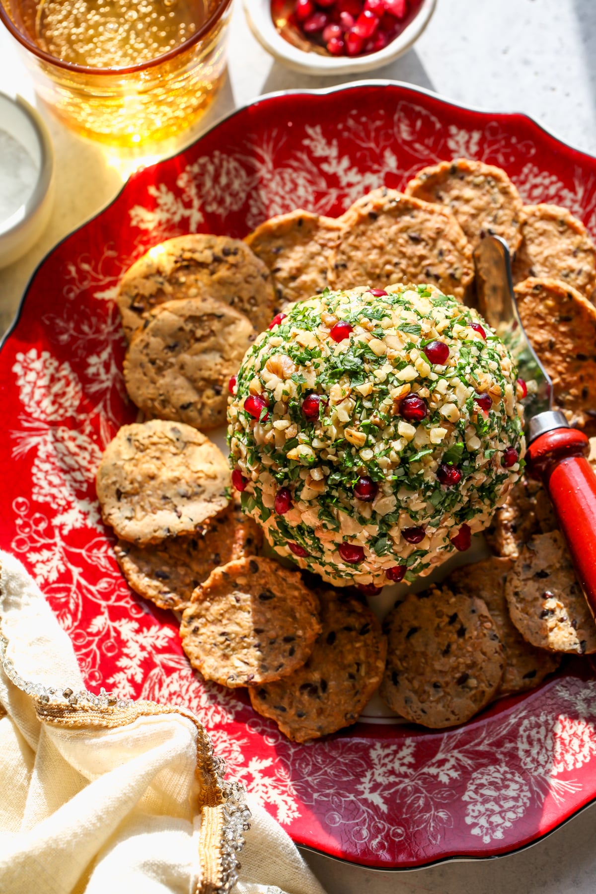 Easy cheese ball with walnuts styled on a red and white plate surrounded by crackers.