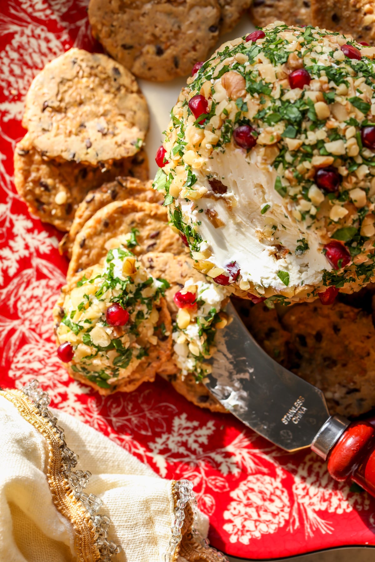 A cracker topped with cheese mixture on a red and white serving plate.