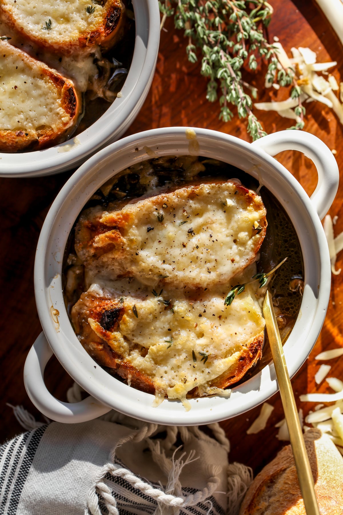 French onion lentil soup topped with cheesy baguette slices in a white bowl.