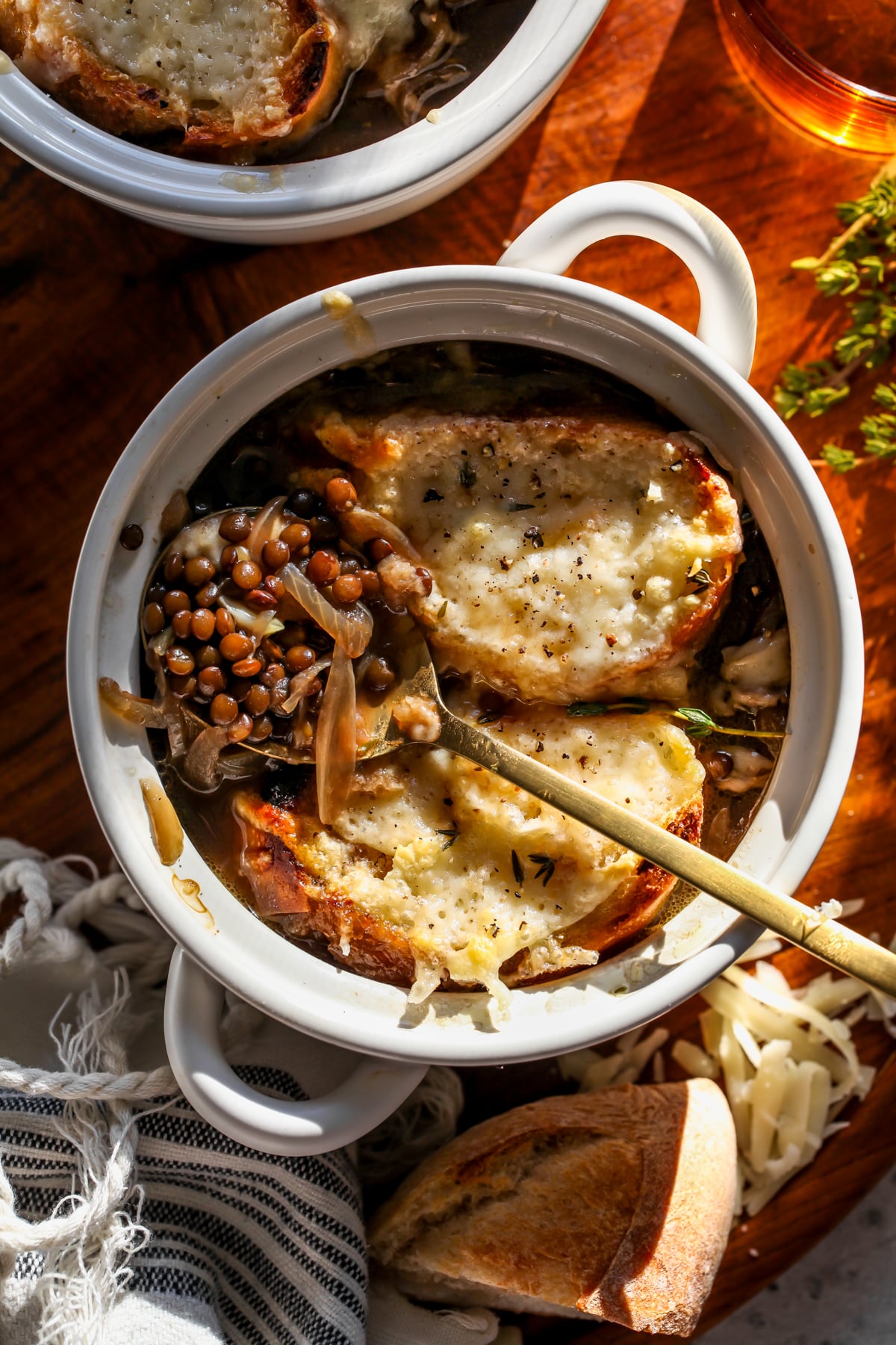 A spoon digging into a bowl of French onion lentil soup to show lentils and broth.