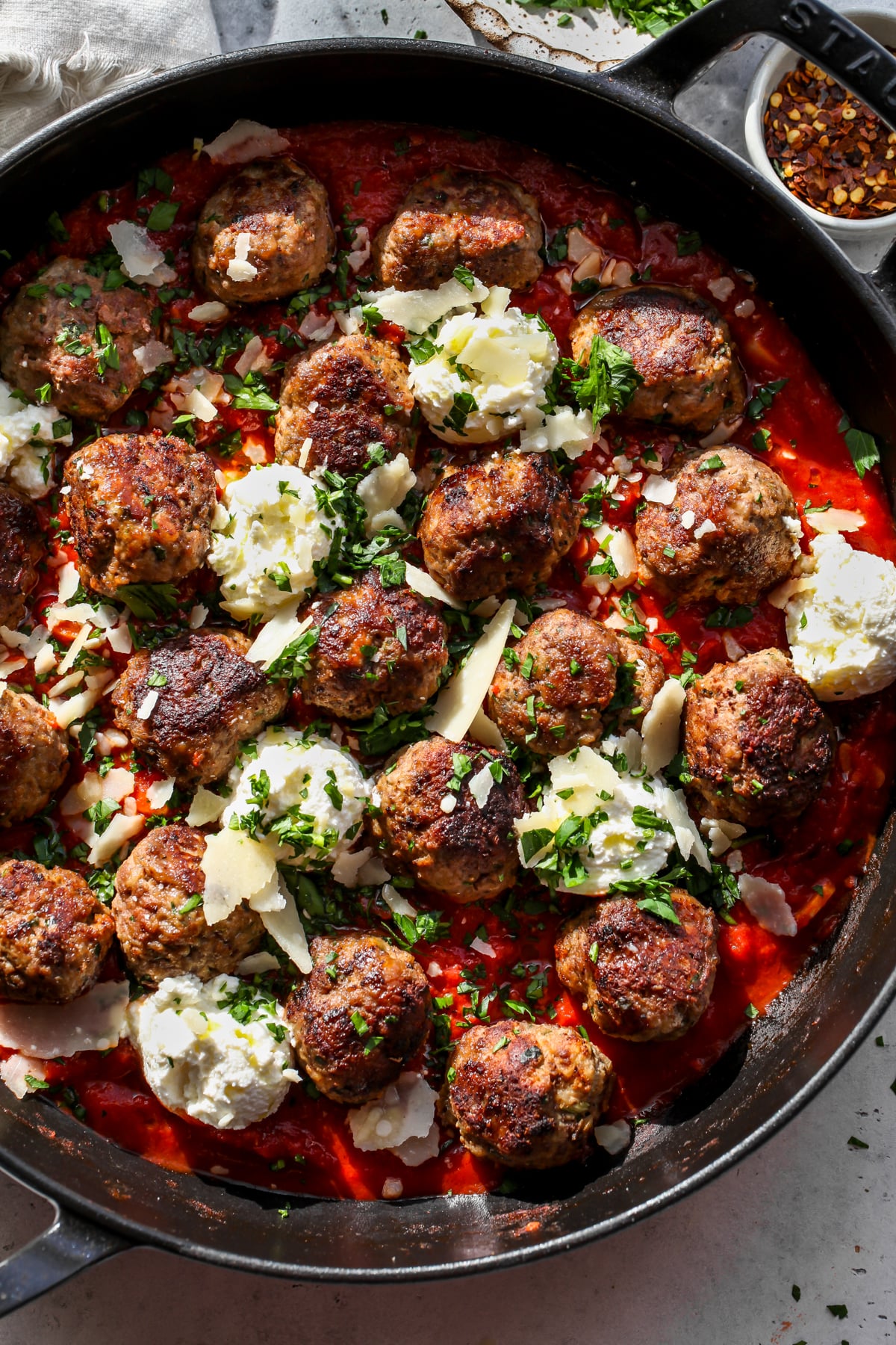 A skillet filled with tomato-basil sauce, ricotta meatballs, and dollops of ricotta cheese.