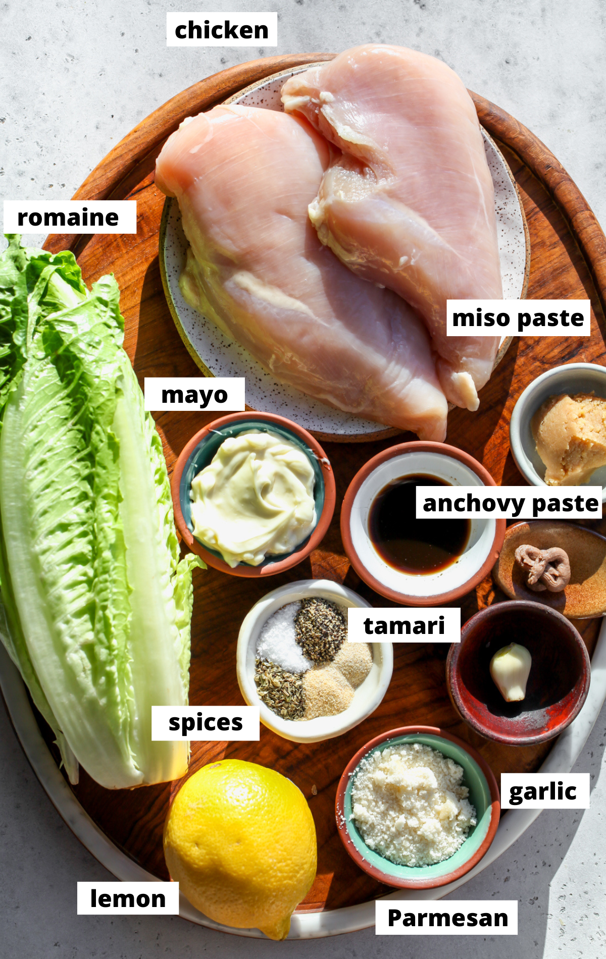 Recipe ingredients in separate bowls assembled on a wooden cutting board.