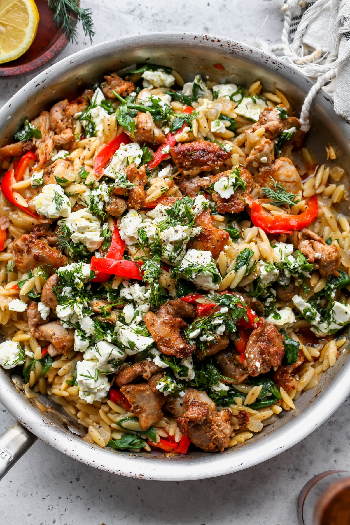 Lemon-Feta Chicken and Orzo styled in a cast iron skillet on a gray surface.